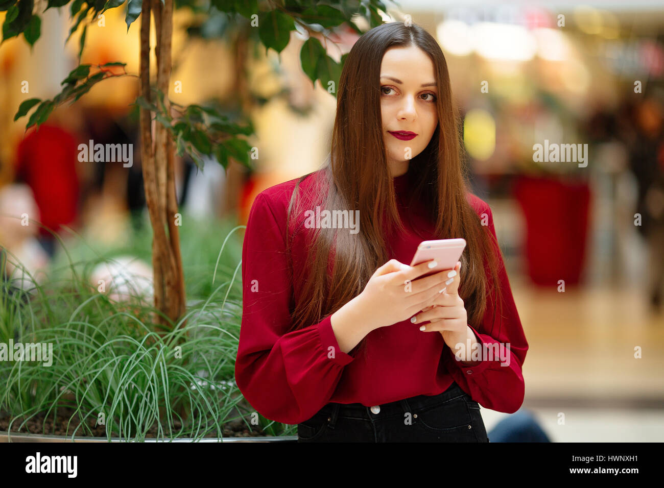 Brünette Frau sitzt auf der Straße und SMS auf dem Handy Stockfoto