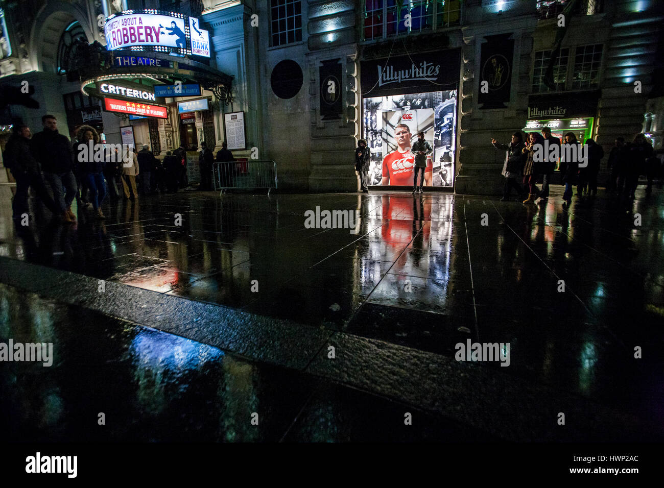 Nachtansicht des Menschen und Reflexionen auf nassen Straßen am Piccadilly circus Stockfoto