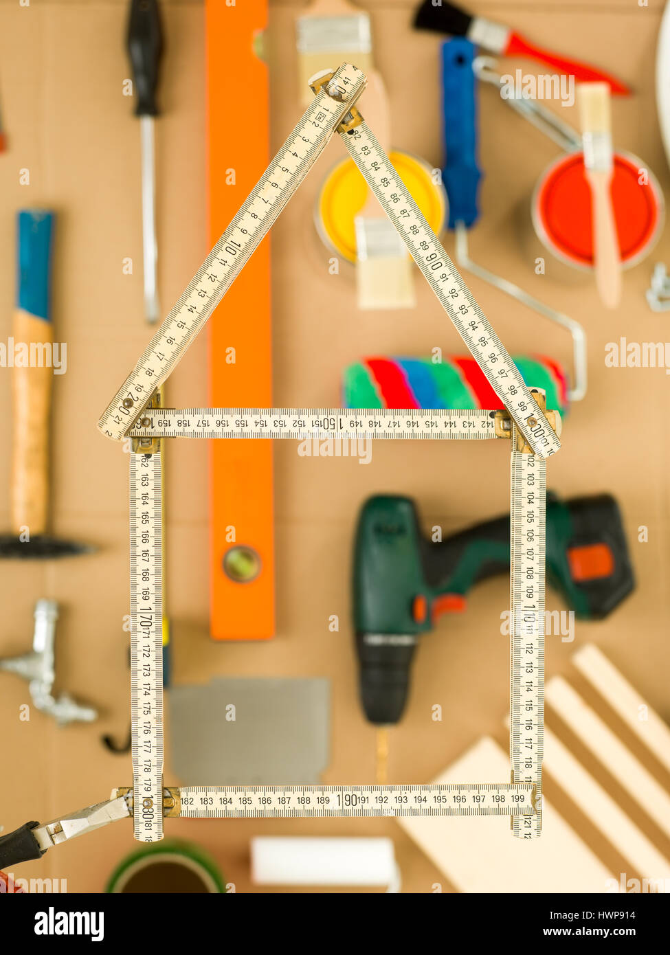Haus-Form gebildet vom Holz Klapp Mess Stick messen mit unscharfen Heimwerkerwerkzeuge im Hintergrund Stockfoto