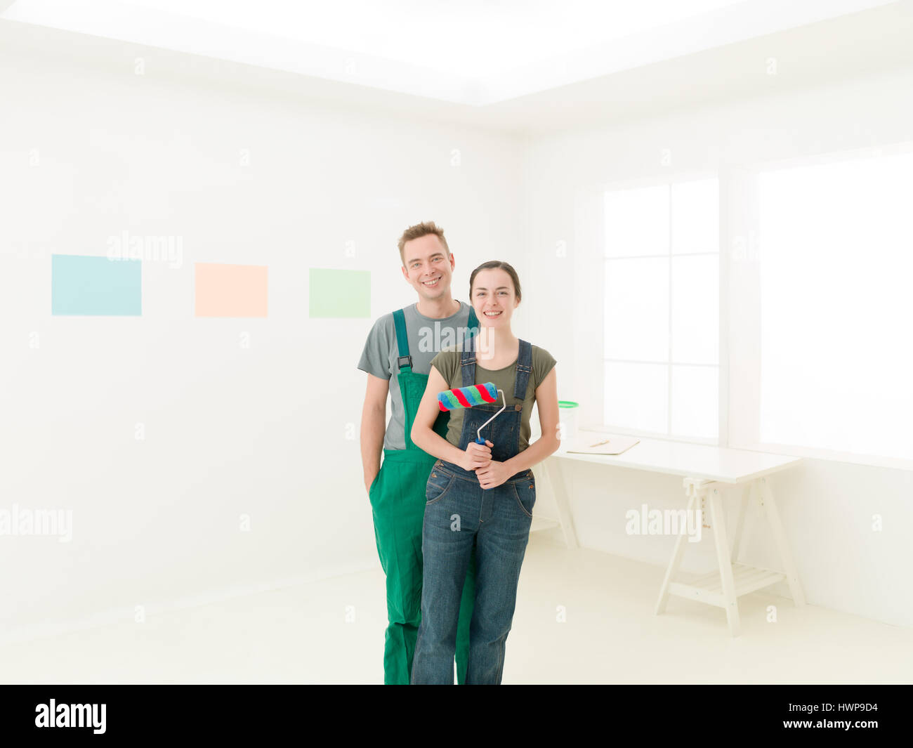 Porträt von ein paar Lächeln hat sie eine Farbe in der Hand Rollen. Reparatur, Bau, Renovierung und Menschen-Konzept Stockfoto