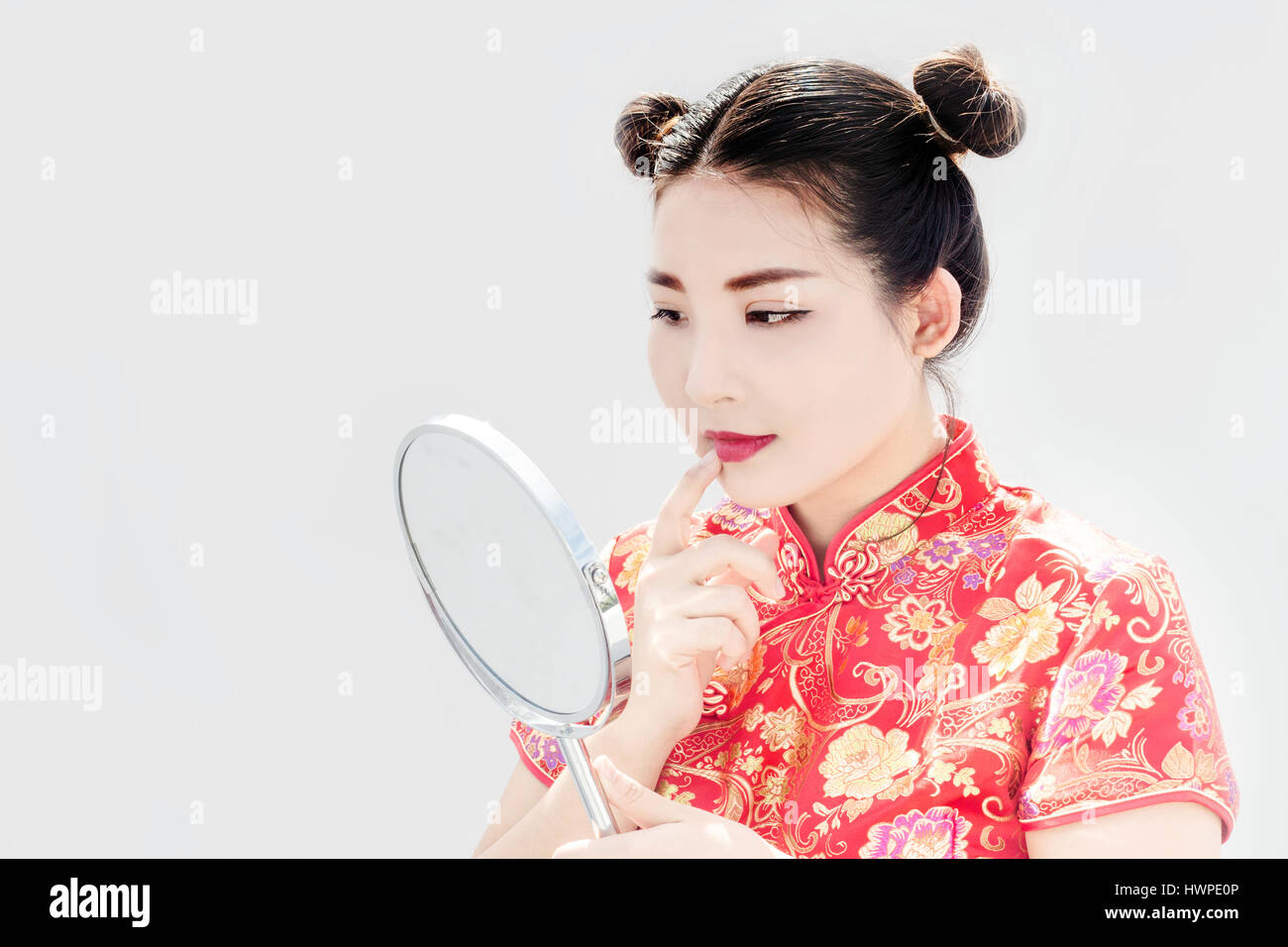 Nahaufnahme der chinesischen Asiatin Check Make-up Gesicht mit Mirrio und Kostüm in Cheongsam China Tradition Kleid in Neujahrsfest auf weißem Hintergrund Stockfoto