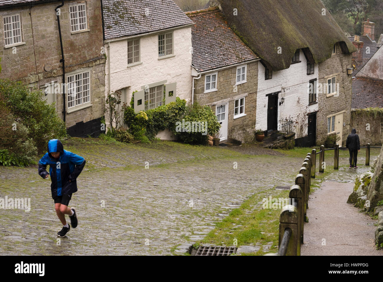 Gold Hill, Shaftesbury, Dorset. 22. März 2017. Laufen in der plötzlichen Regenguss die ikonische gepflasterten Straße Gold Hill hinauf. Bildnachweis: David Hansford Fotografie/Alamy Live-Nachrichten Stockfoto