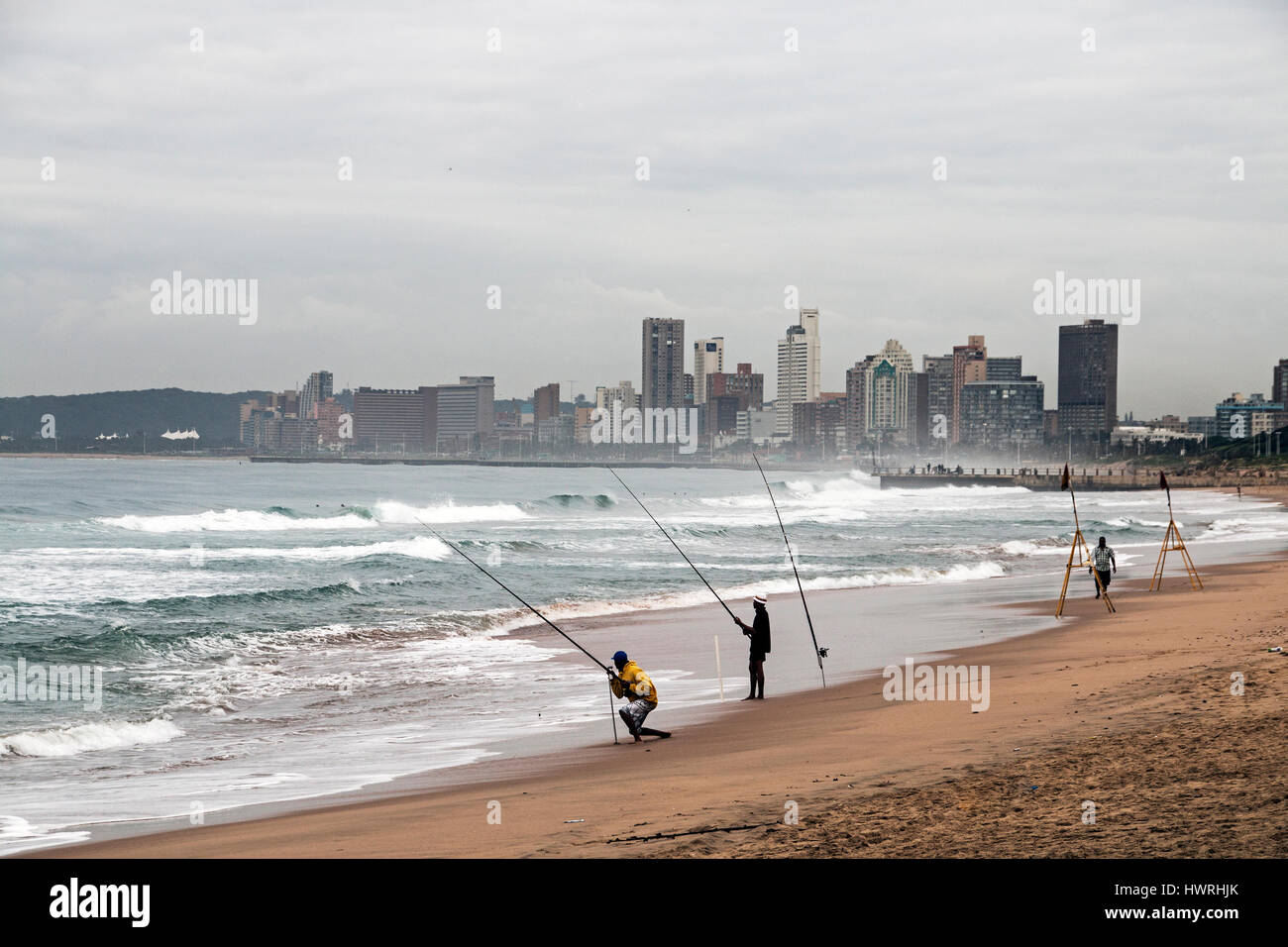 DURBAN, Südafrika - 23. März 2017: drei unbekannte am frühen Morgen Fischer am Strand gegen bewölkten Skyline von Durban in Südafrika Stockfoto