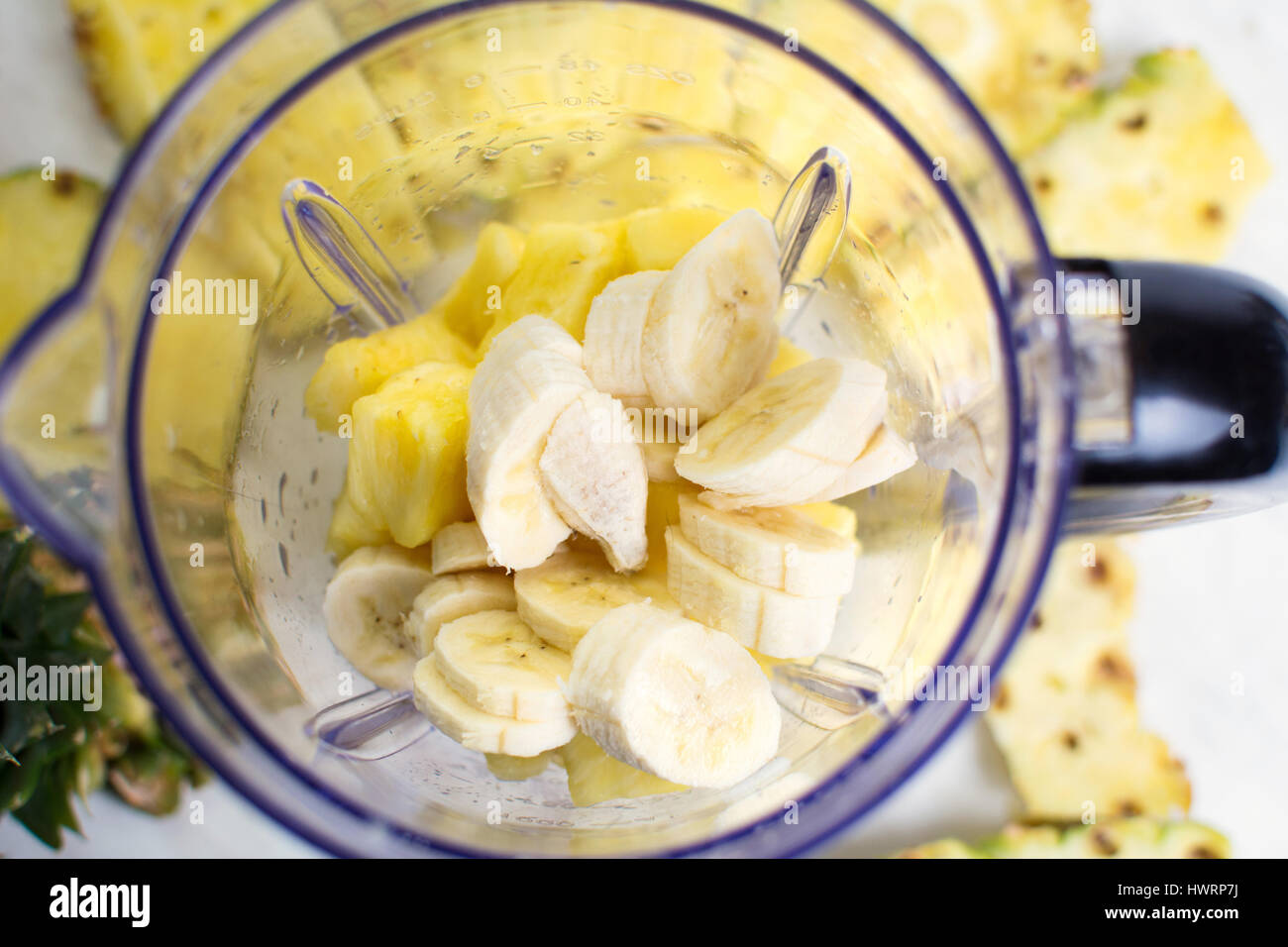 In Scheiben geschnittene Ananas und Banane in einen Mixer geben Stockfoto
