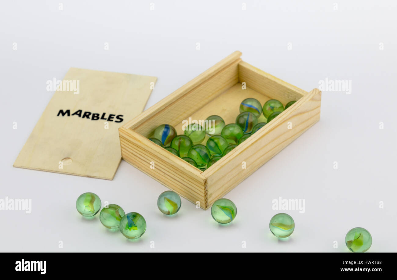 Holzbox aus grünem Glasmurmeln auf weißem Hintergrund Stockfoto