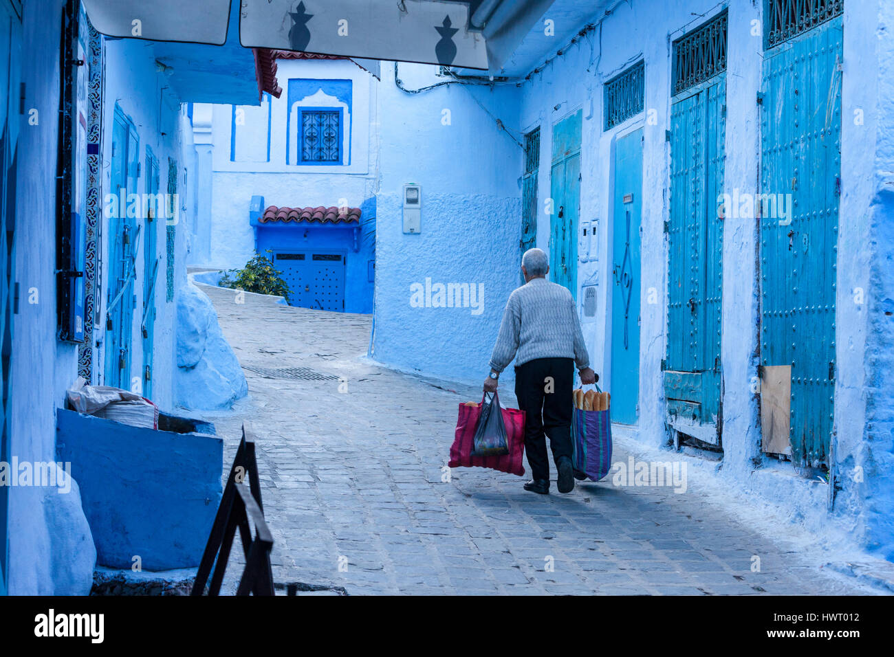 Chefchaouen, Marokko.  Mann trägt Brot und andere Einkäufe auf dem Markt. Stockfoto