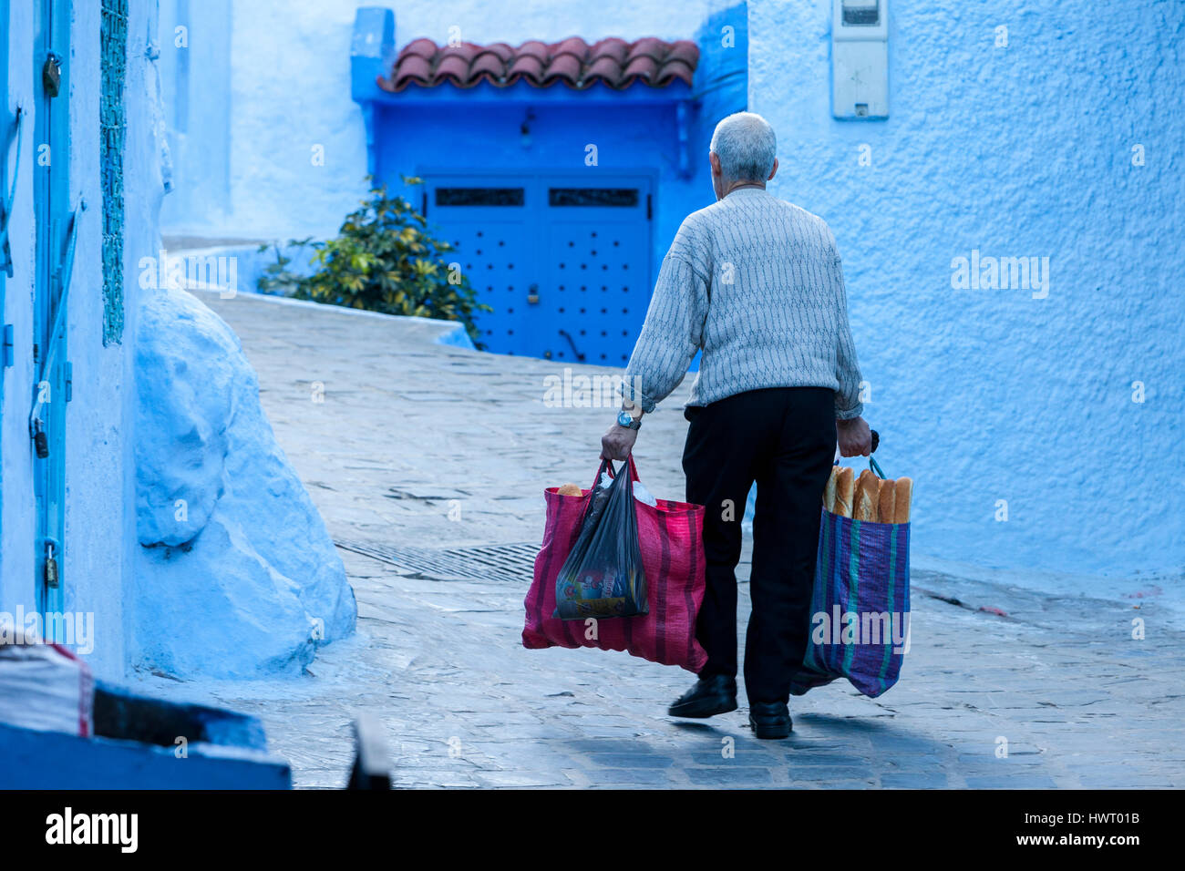 Chefchaouen, Marokko.  Mann trägt Brot und andere Einkäufe auf dem Markt. Stockfoto
