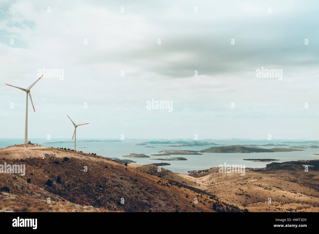 Windmühlen auf Hügel gegen bewölktem Himmel auf dem Seeweg Stockfoto