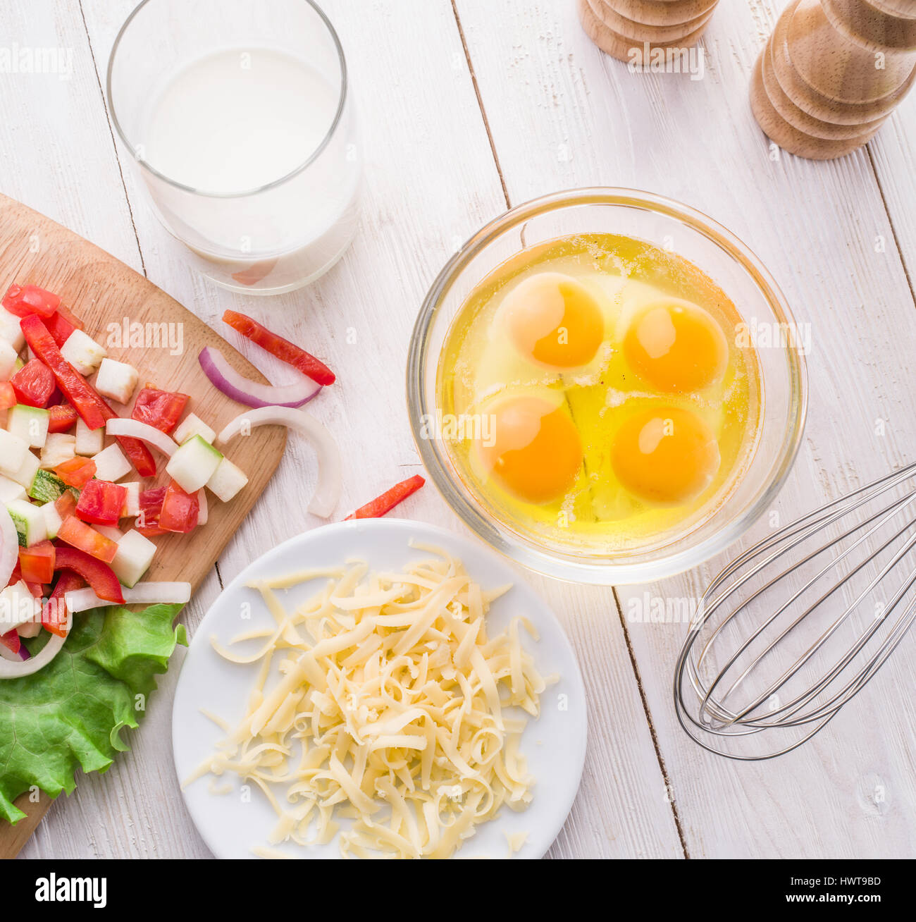 Omelett-Zutaten: Eiern, frisch geschnittene Gemüse, Milch und Käse auf dem Holztisch. Stockfoto