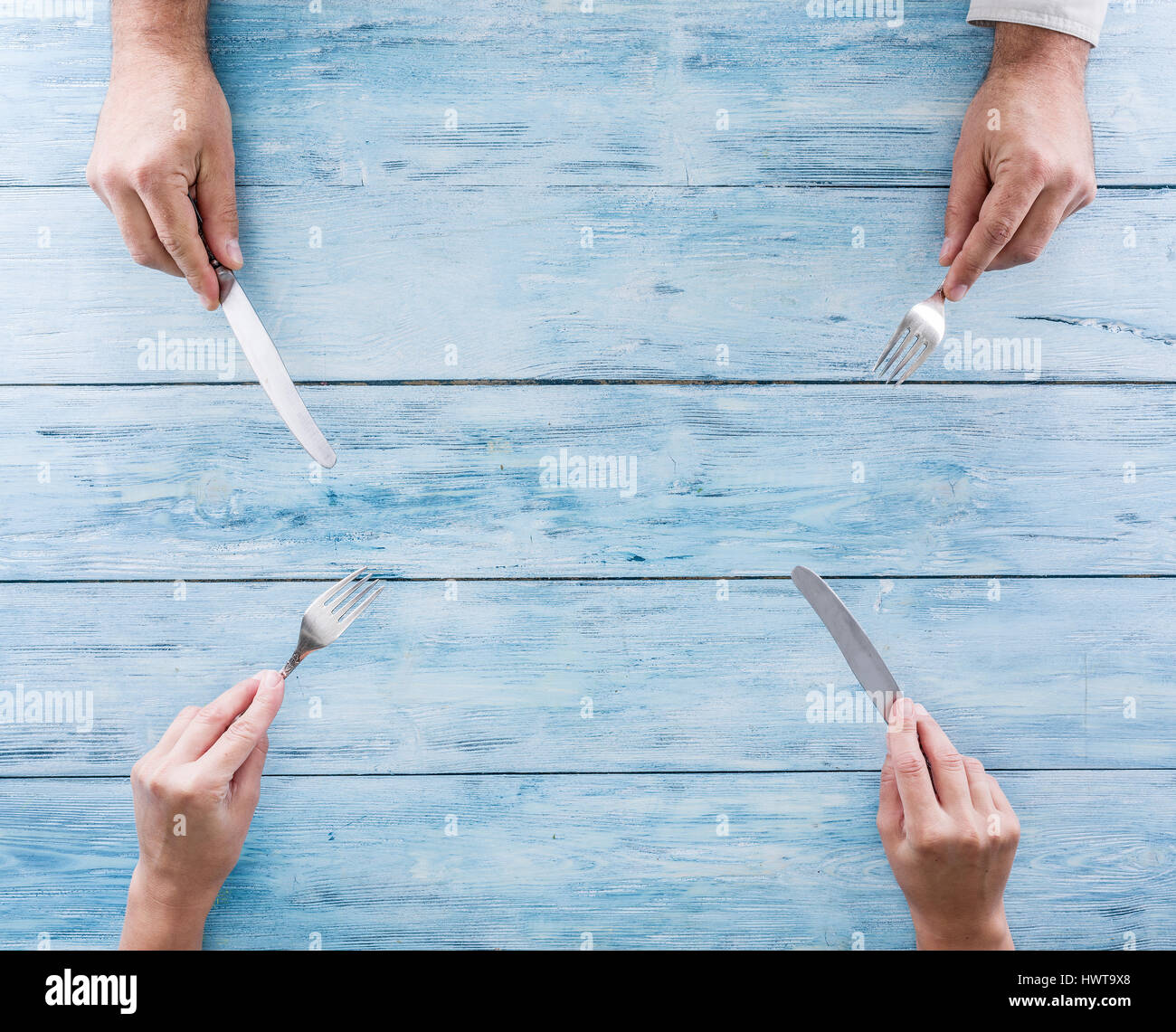 Blaue leere Tabelle und Besteck in der menschlichen Hand. Ansicht von oben. Stockfoto