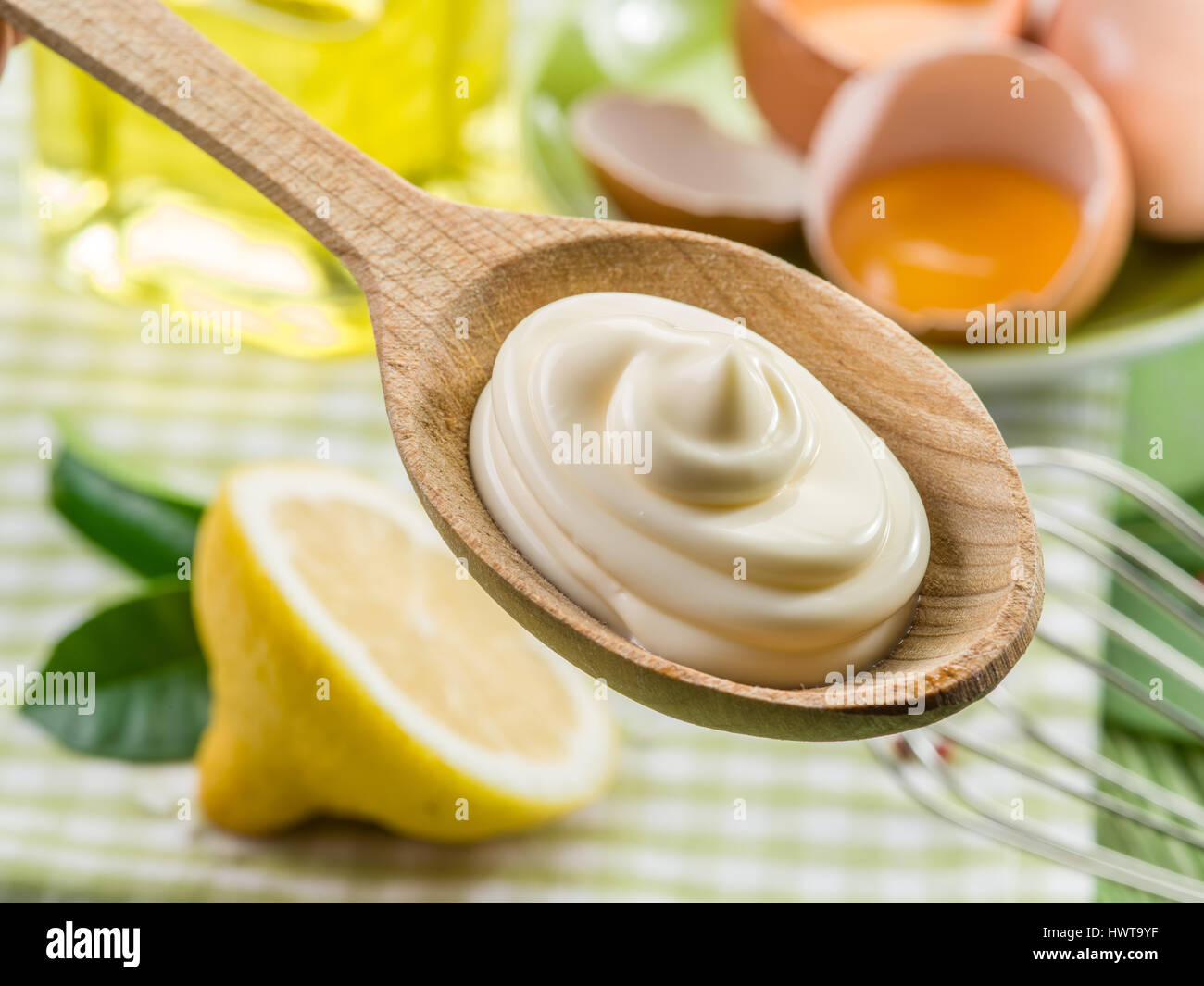 Natürliche Mayonnaise Soße in den Kochlöffel und die Zutat auf dem Hintergrund. Stockfoto