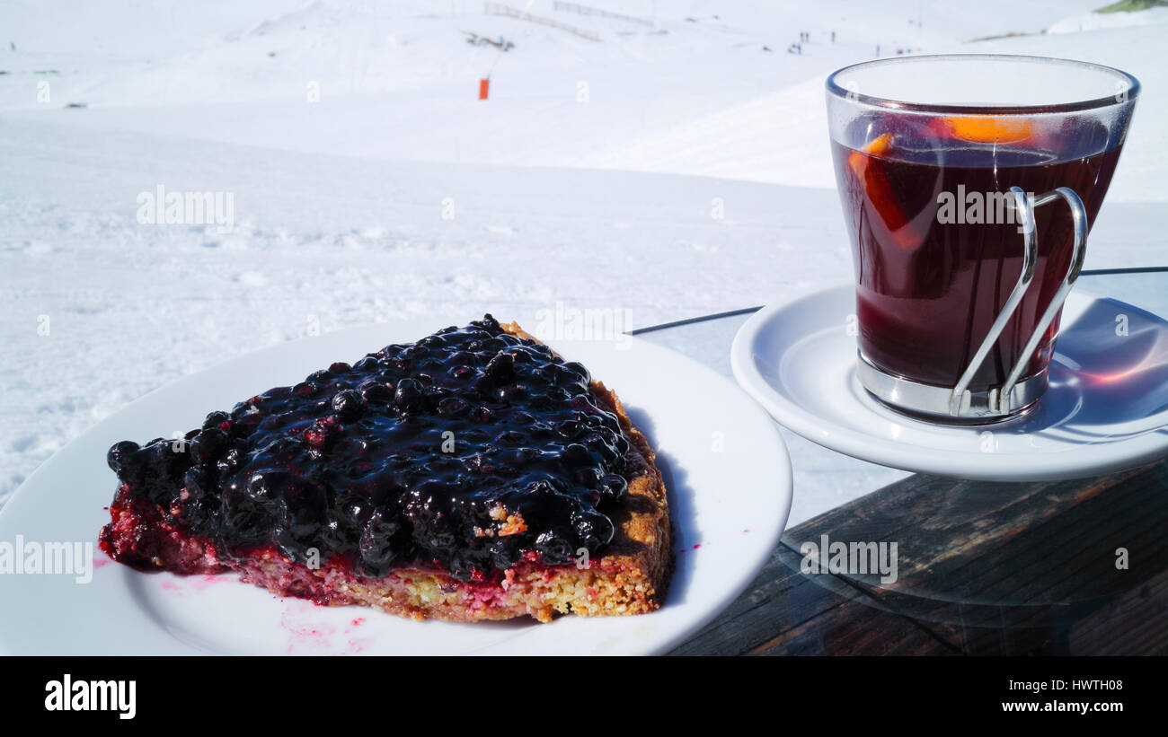 Heidelbeer-Kuchen, Glühwein in einem Glas serviert im Freien auf der Skipiste in französischen Alpen Stockfoto