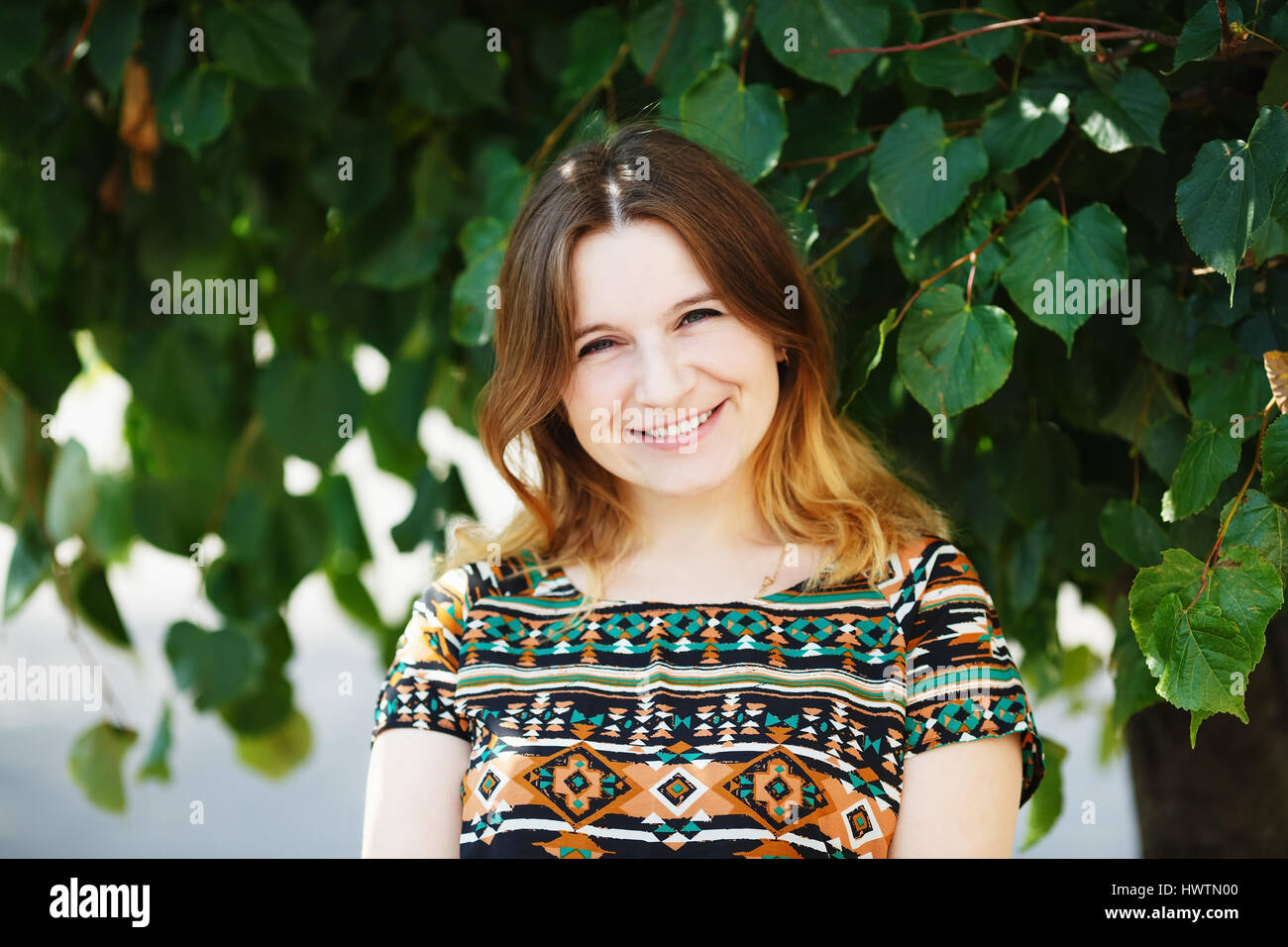 Glücklich lächelnde Frau auf grünem Laub Hintergrund. Geringe Schärfentiefe. Selektiven Fokus. Stockfoto