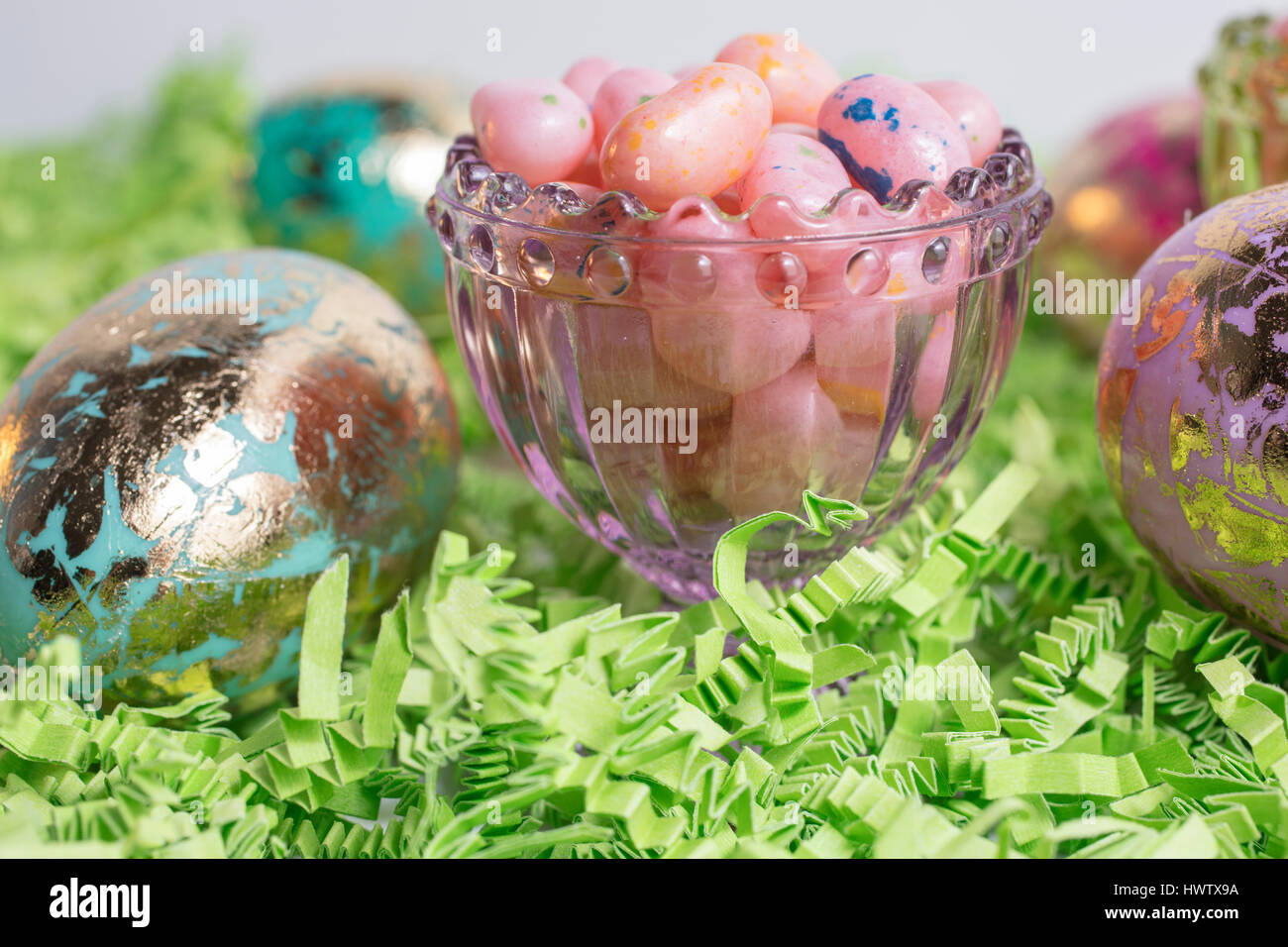Ostereier und Jelly Beans in einem Glasbehälter und auf grünem Krepp-Papier Stockfoto