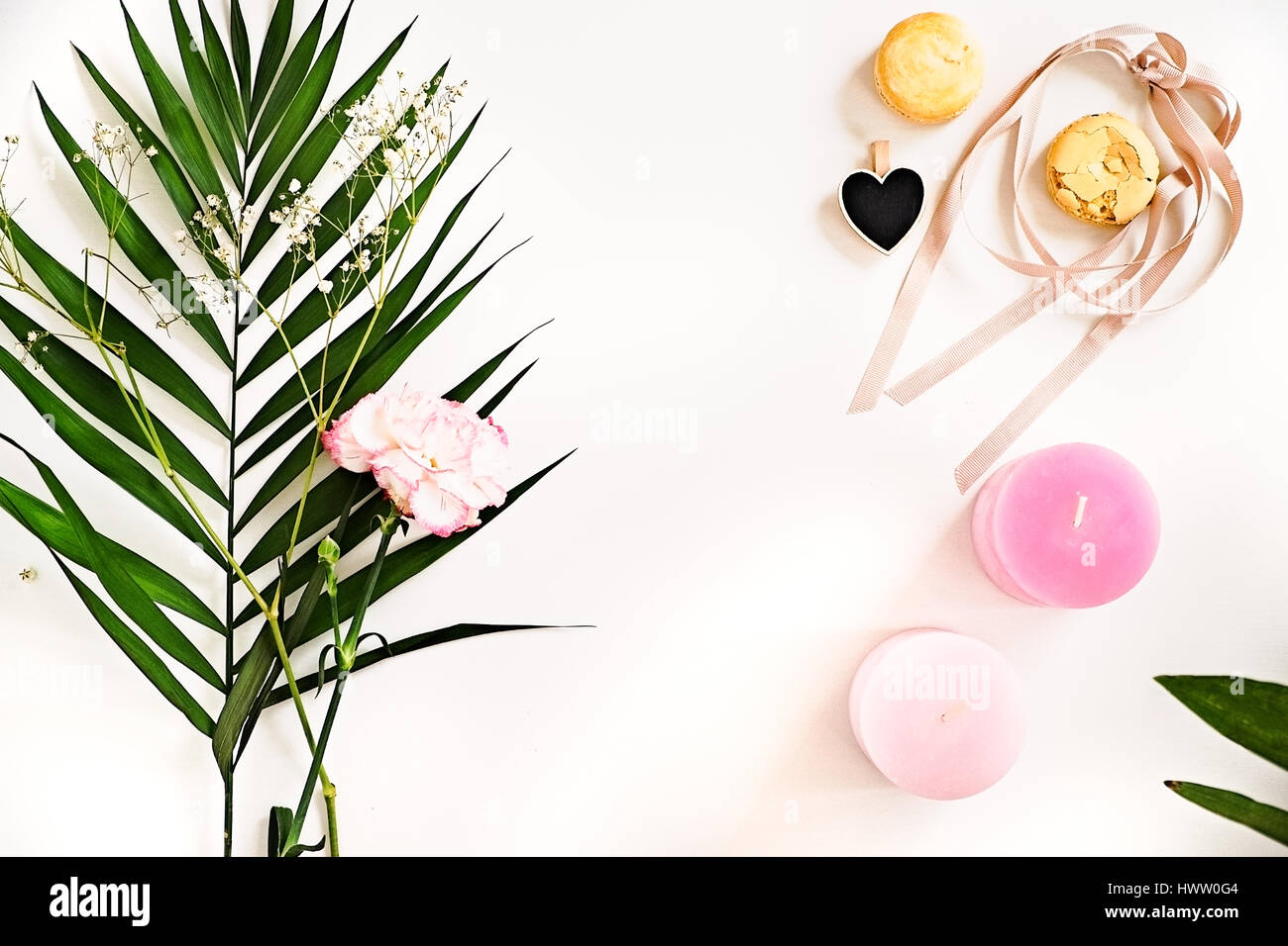 Beauty Blogger flach legen auf weiß.  Grüne Blätter und Nelke Blume, rosa Ombre Kerzen, Herzen, Makronen. Frau, Deko-Ideen. Negativer Raum für Stockfoto