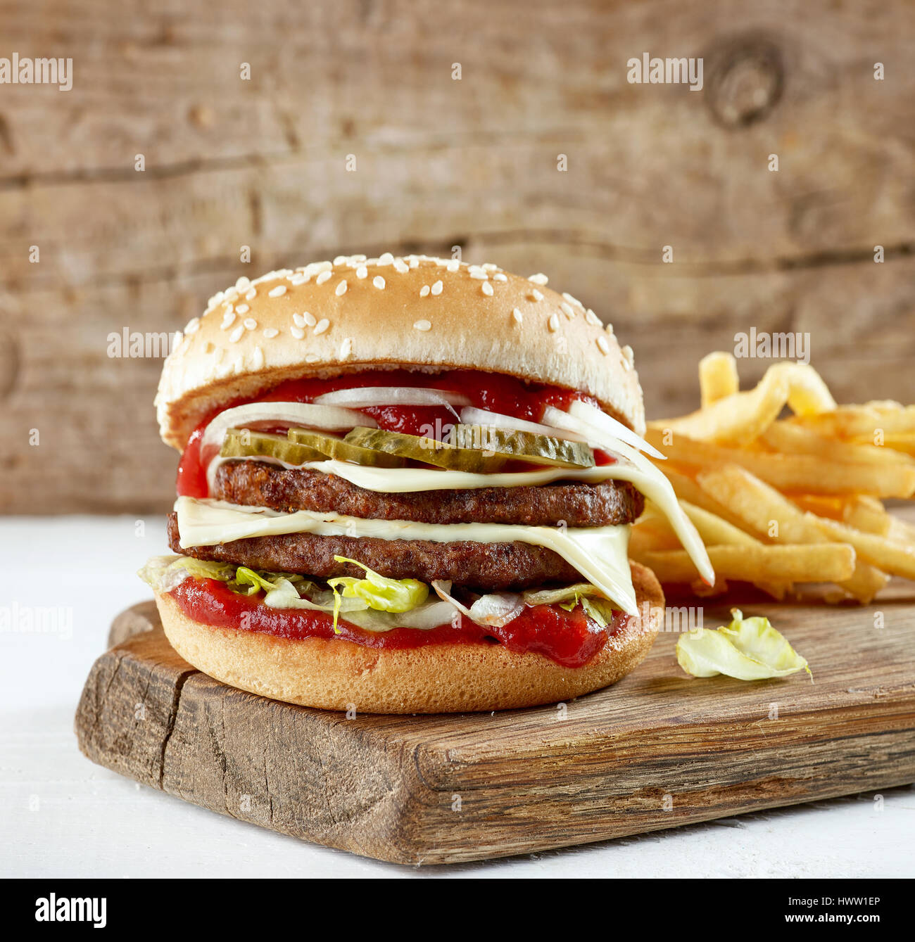 frische leckere Burger und Kartoffeln auf Holzbrett Stockfoto