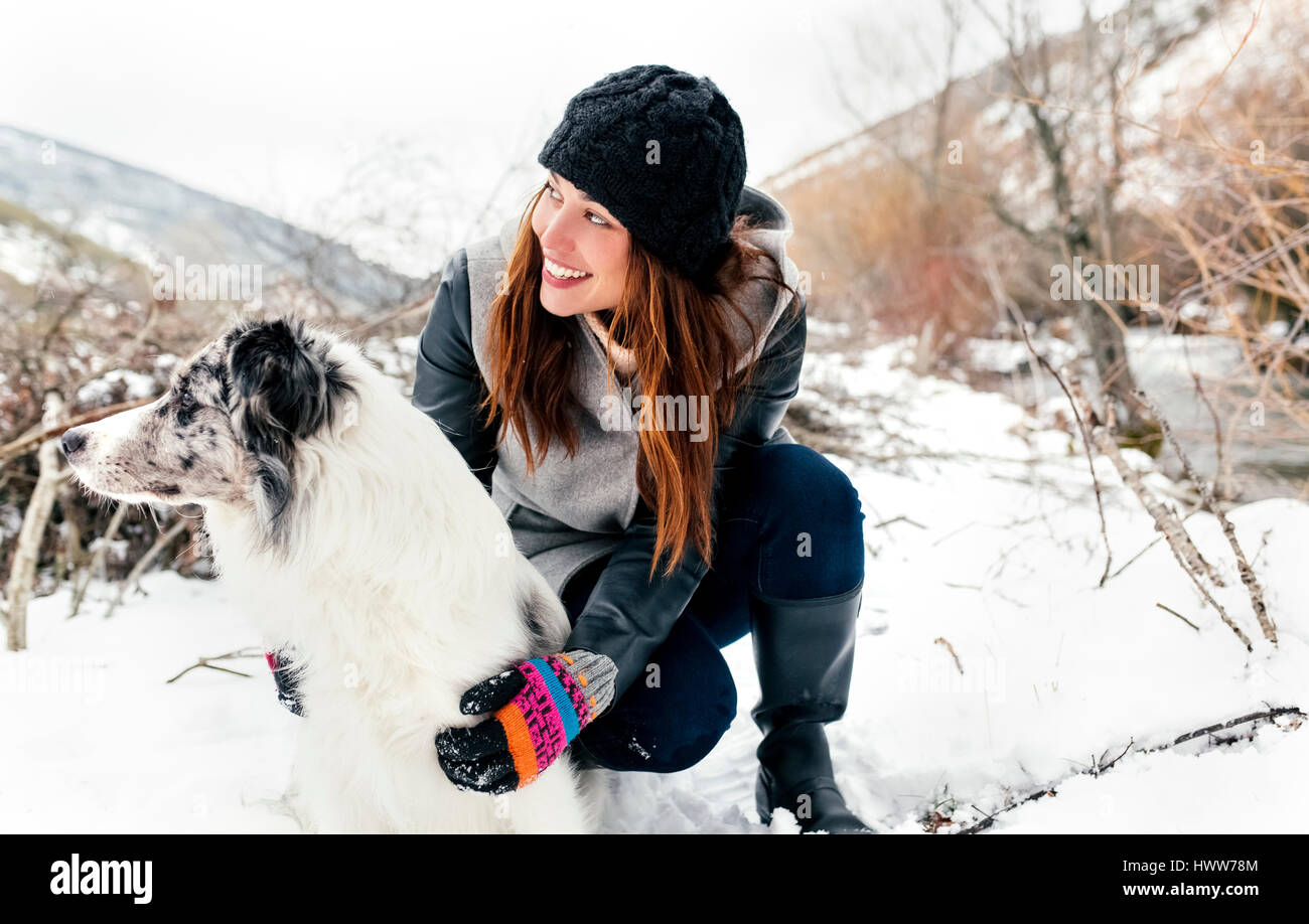 Junge Frau mit ihrem Hund im Schnee spielen Stockfoto