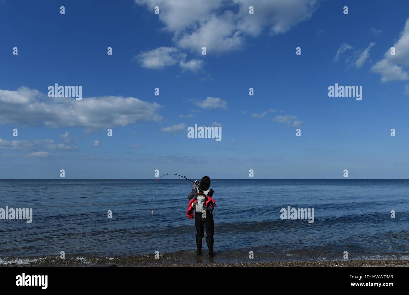 Ein Fischer wirft ihre Linie am Ostsee-Strand in Weissenhaus, Deutschland, 22. März 2017. Foto: Carsten Rehder/dpa Stockfoto