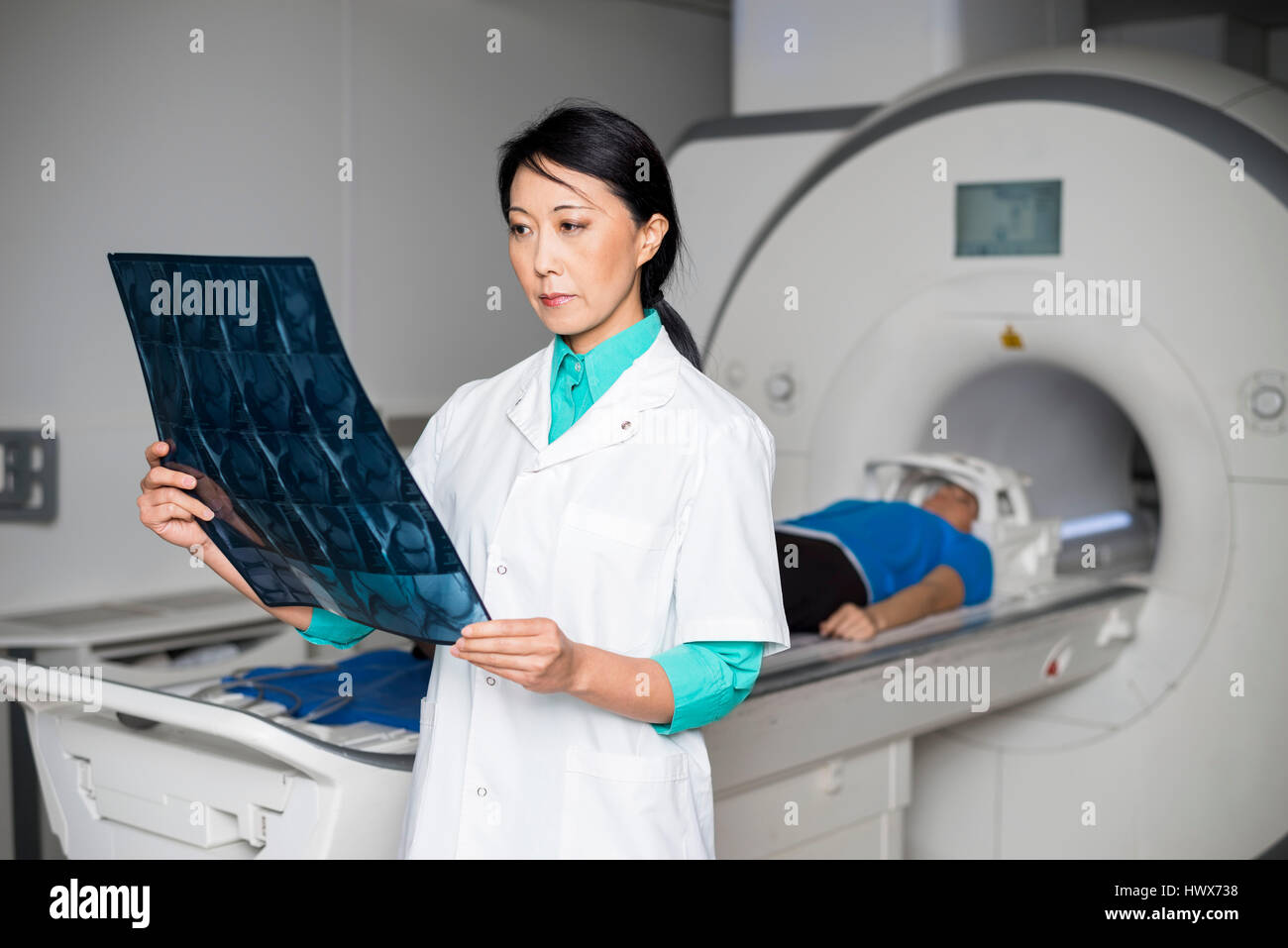 Ärztin, die Analyse von x-ray beim Patienten liegen auf MRT-Scan-Gerät im Krankenhaus Stockfoto