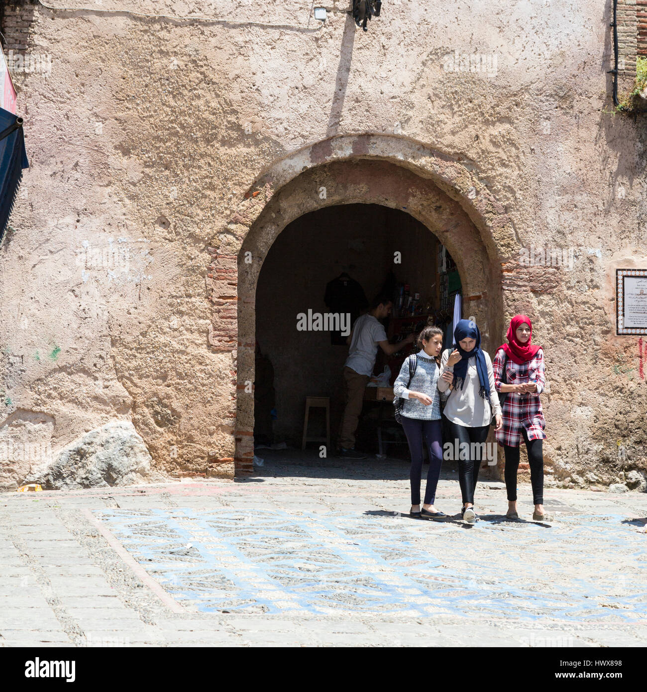 Chefchaouen, Marokko.  Junge marokkanische Frauen verlassen die Medina durch die Bab El-Ain, moderne stilvollen, aber konservative Kleidung zu tragen. Stockfoto