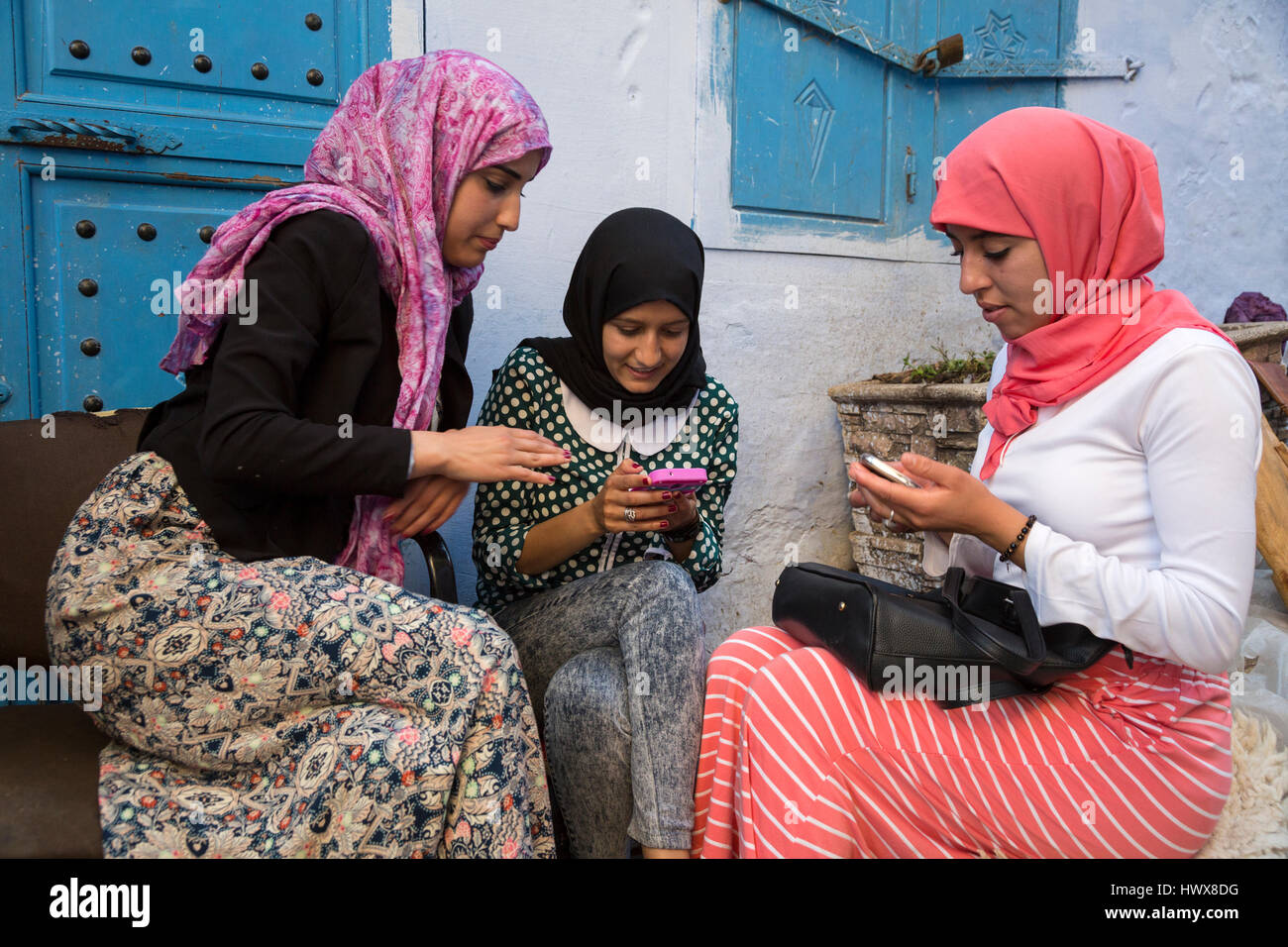 Chefchaouen, Marokko.  Junge arabische Frauen überprüft ihre Handys. Stockfoto