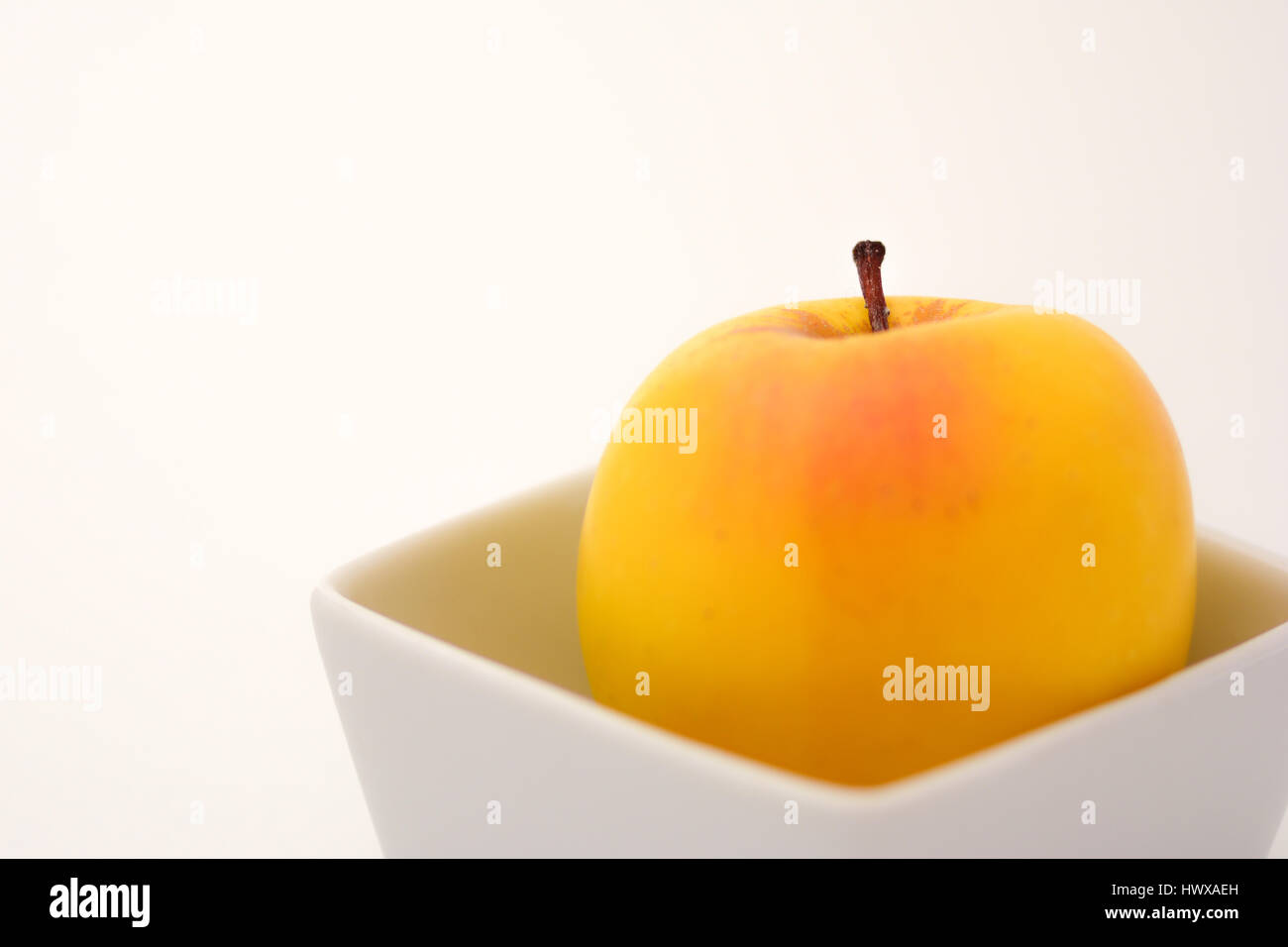 Eine Nahaufnahme von einem einzigen Goldenen Apfel in einem quadratischen Behälter Stockfoto