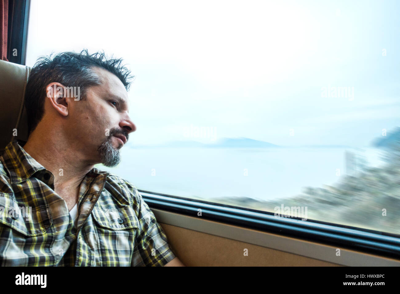 Ein Mann aus dem Fenster auf einen Zug in der Nähe von Wasser. Stockfoto