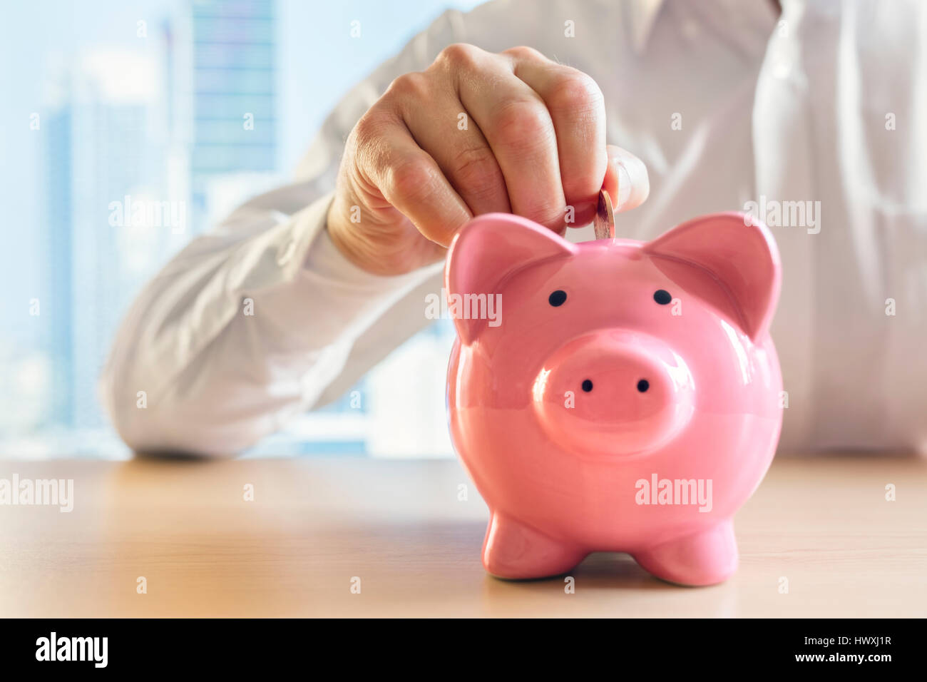 Mann, eine Münze in ein rosa Sparschwein-Konzept für Einsparungen und Finanzen Stockfoto