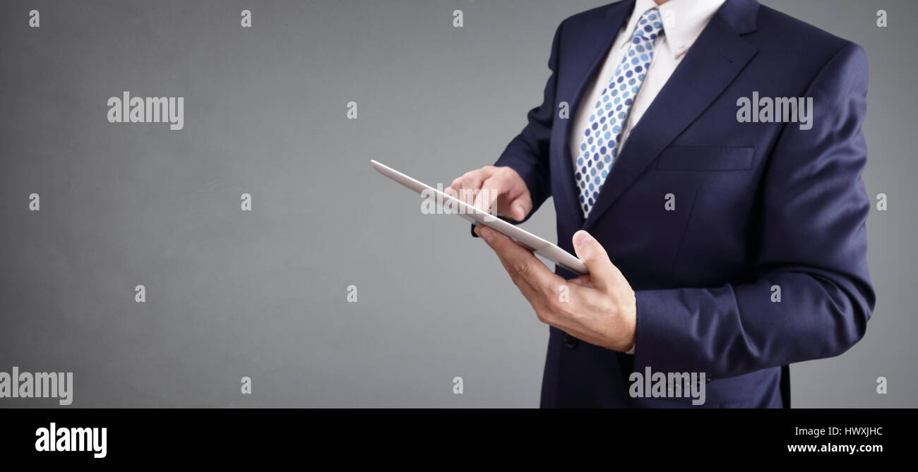 Geschäftsmann mit Tablet-Computer und grauem Hintergrund zum Kopieren Stockfoto