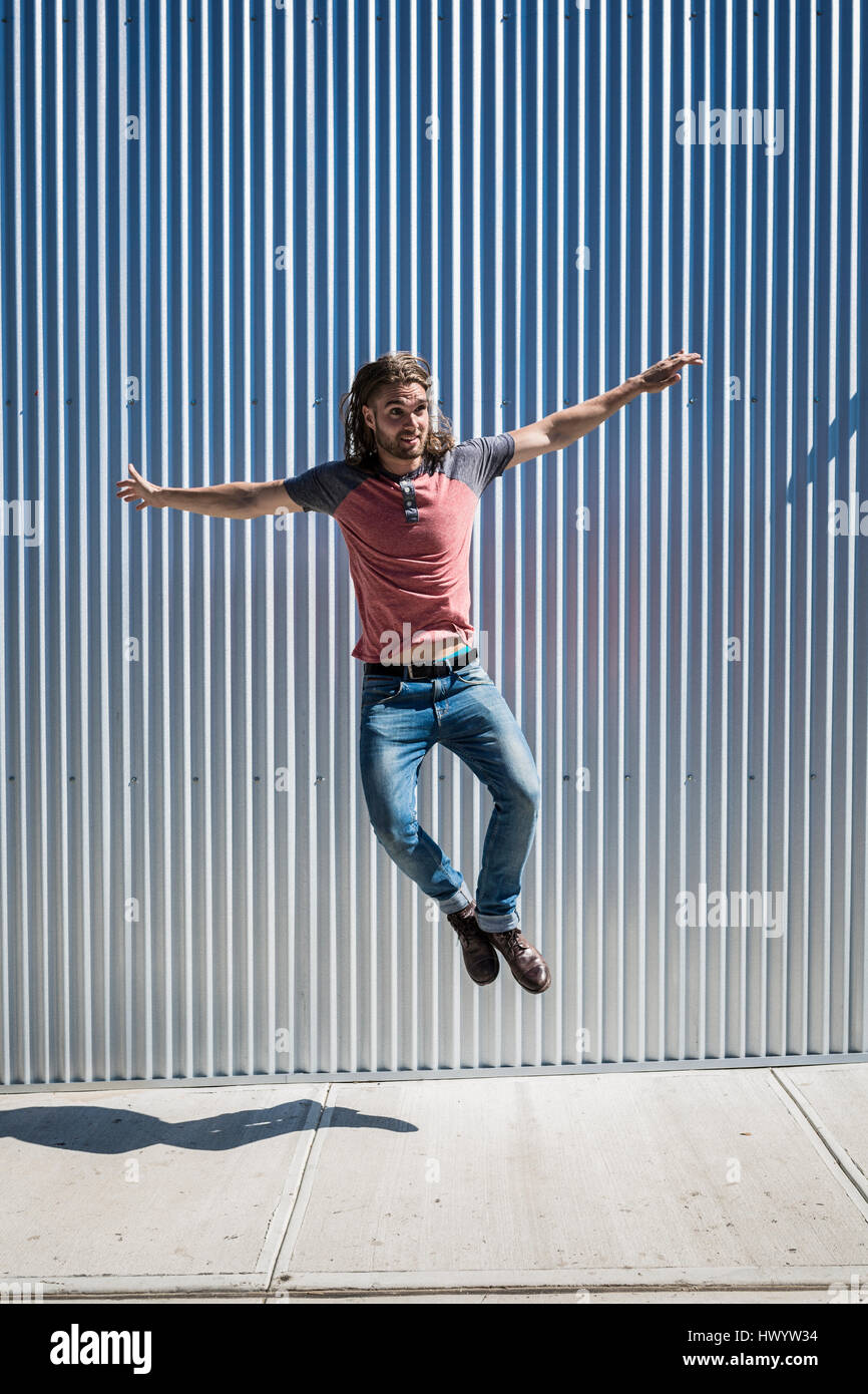 Mann springt mitten in der Luft auf Bürgersteig Stockfoto