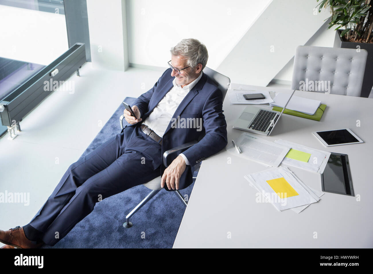 Lächelnde Geschäftsmann mit Handy im Büro Stockfoto