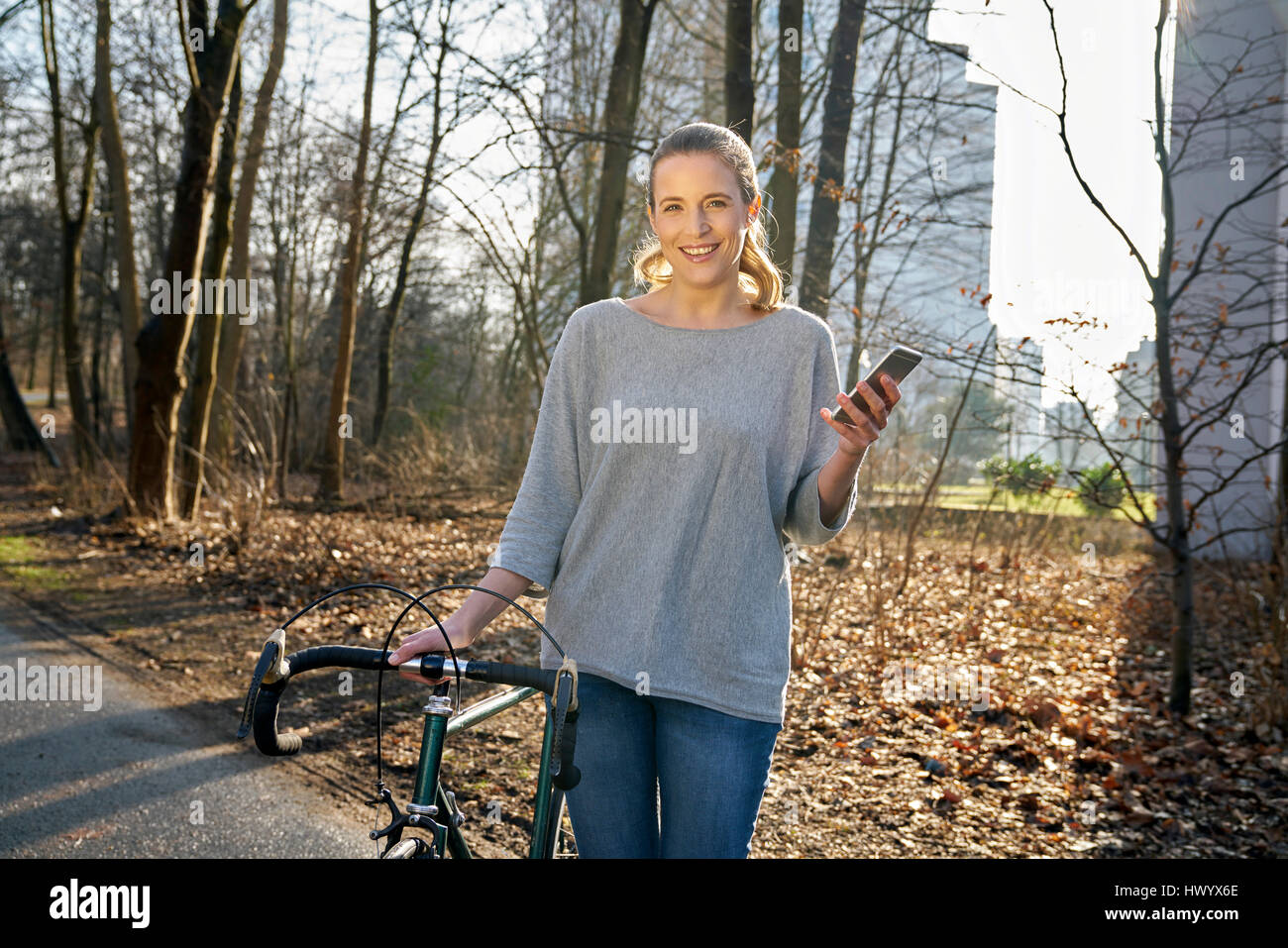 Porträt von lächelnden blonden Frau mit racing-Zyklus und Handy Stockfoto