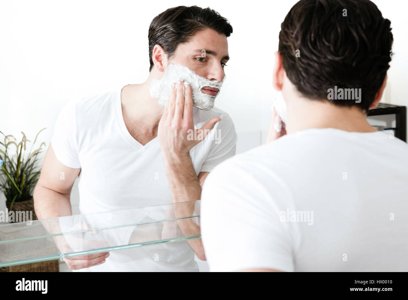 Junger Mann stand vor dem Spiegel, Rasierschaum auftragen Stockfoto