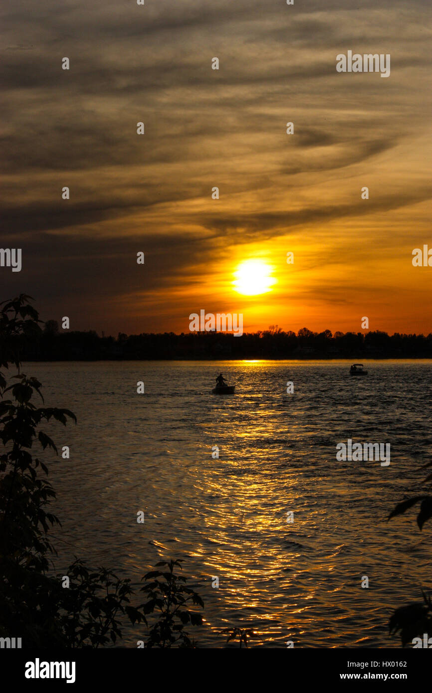 Silhouette Menschen Angeln von einem Boot bei Sonnenuntergang Stockfoto