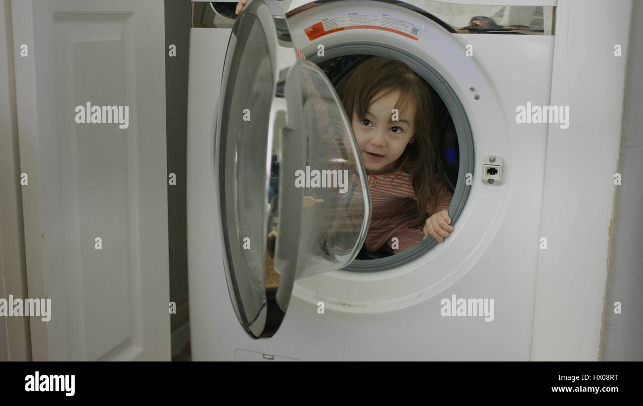 Selektiven Fokus hautnah erkunden spielerische Mädchen versteckt in Waschmaschine Stockfoto