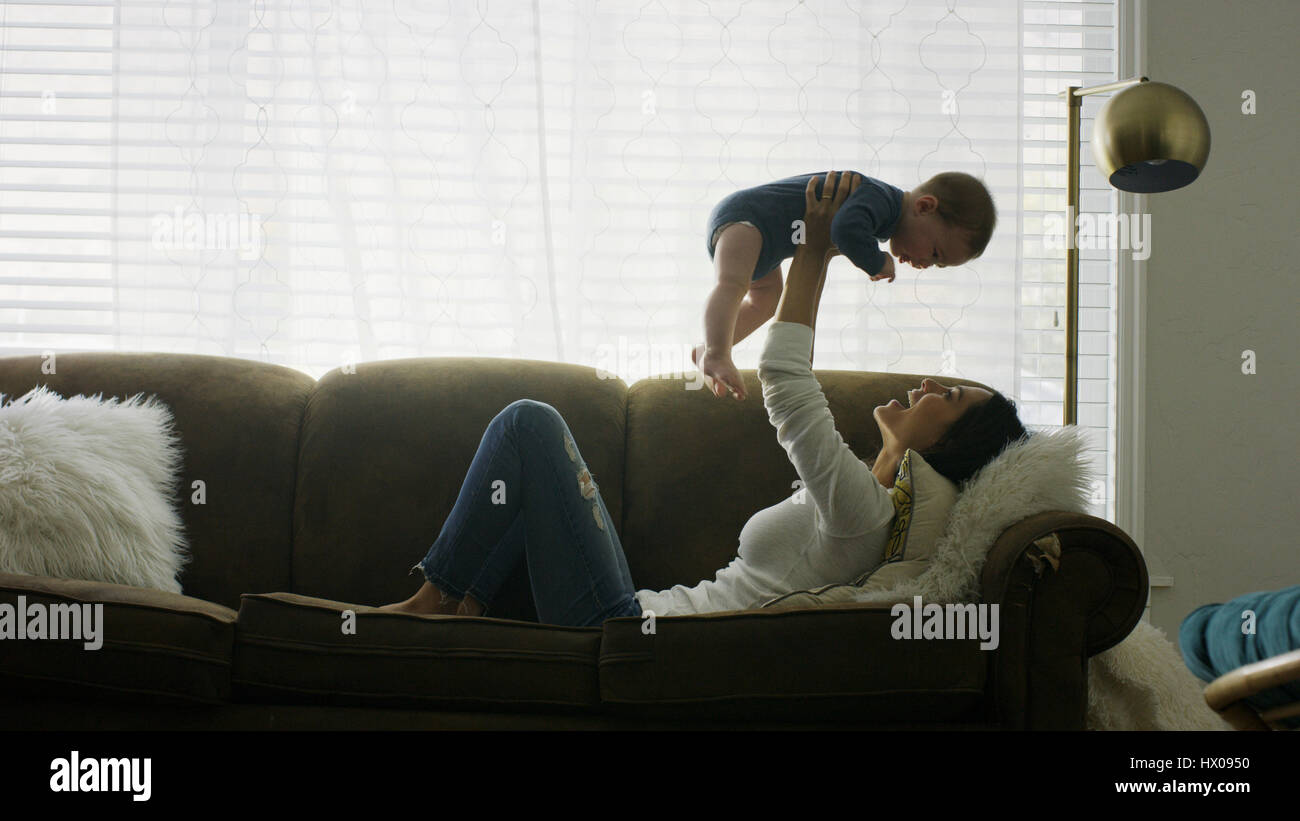 Profil von verspielten Mutter Sohn in der Luft lachend und spielend auf sofa Stockfoto