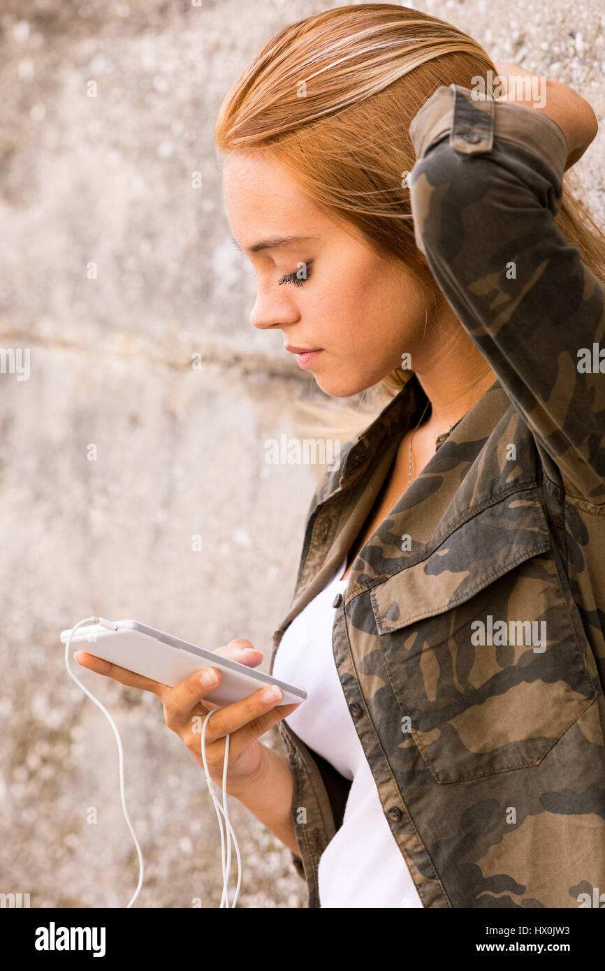 Mädchen mit ihrem Handy auf den Straßen, Leben im Freien, wie eine moderne junge Frau, SMS und ihre Lieblingsmusik hören Stockfoto