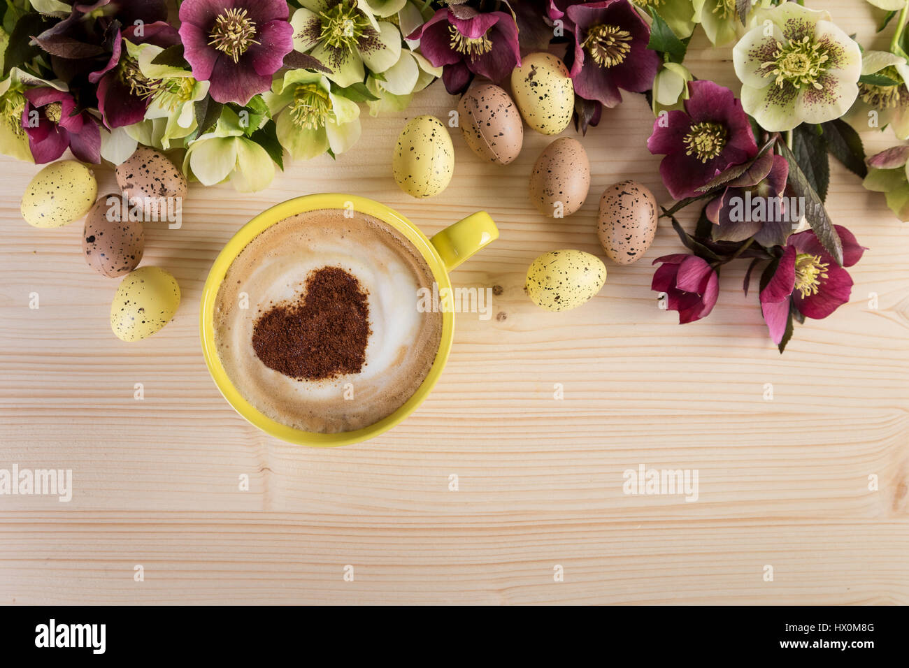 Kaffee Tasse Cappuccino mit Oster-Deko auf leichte Holztisch. Herz-Form-Schaum, Ansicht von oben. Stockfoto