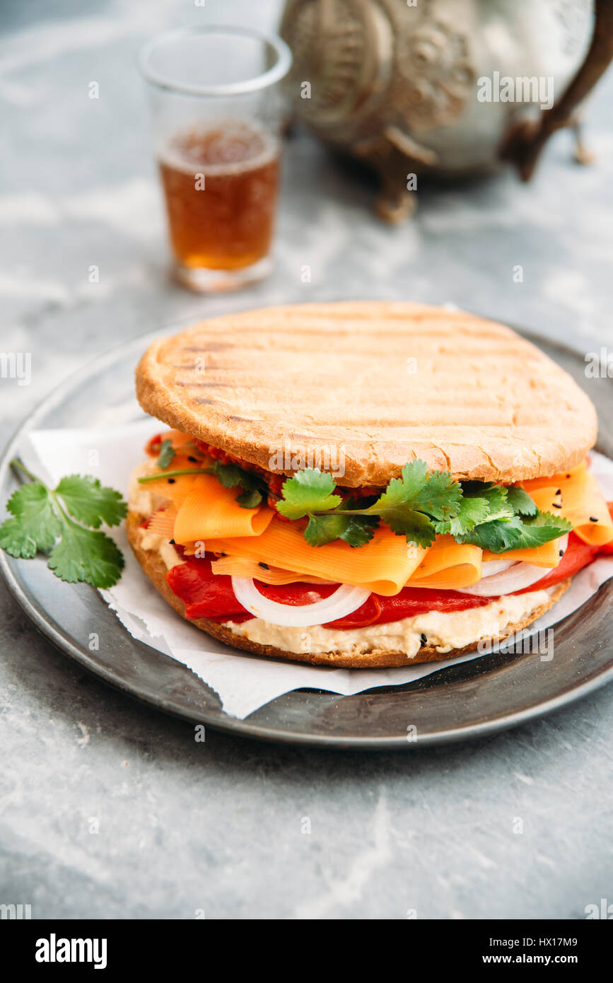 Marokkanischen Stil Sandwich mit Hummus, gegrilltem Paprika, Zwiebeln, Karotten, Koriander, Ajvar, Schwarzkümmel Stockfoto