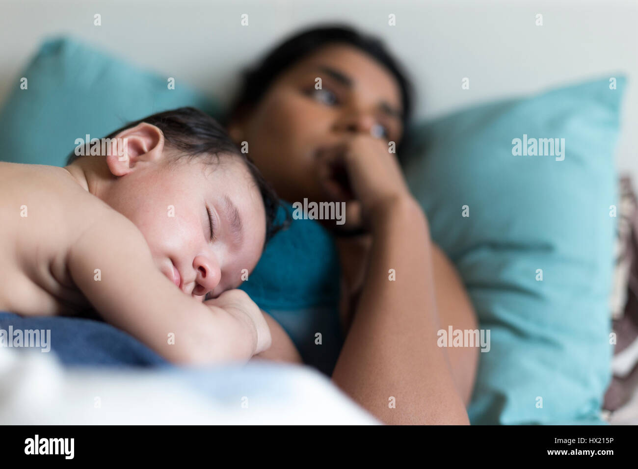 Baby schlafend im Bett auf seiner Mutter Brust, die Pause vom stressigen genießt Elternschaft. Stockfoto