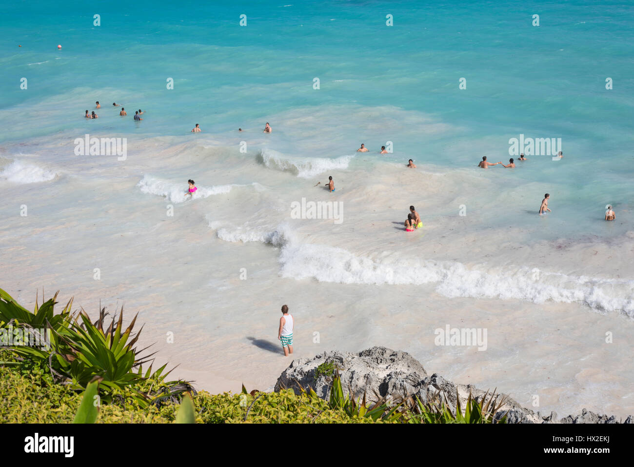 Draufsicht auf das Karibische Meer unter blauem Himmel mit Badenden am Strand von Tulum, Halbinsel Yucatan, Mexiko, grüne tropische Pflanze Palmen Bäume foregroun Stockfoto