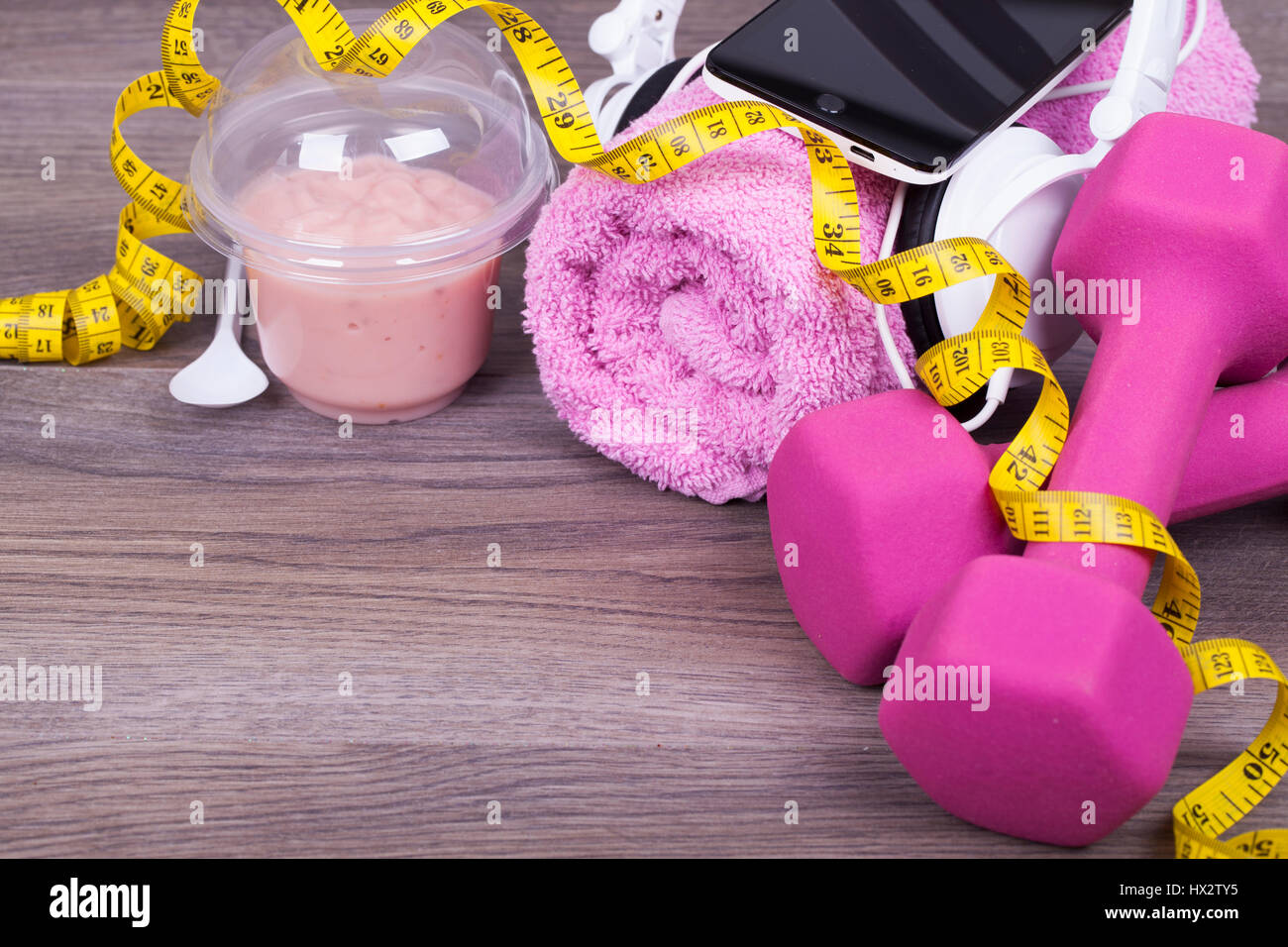 Fitness-Konzept mit einem Handy und Kopfhörer, Gewichte, Handtuch und Obst Joghurt auf einem hölzernen Hintergrund. Mit dem leeren Raum für Ihren text Stockfoto