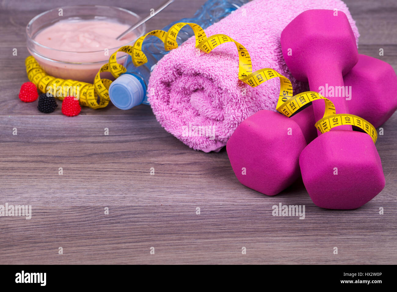 Fitness-Konzept mit einer Flasche Wasser, Gewichte, Handtuch, Apfel und sehr leckeren Fruchtjoghurt auf einem hölzernen Hintergrund. Mit dem leeren Raum für Ihren Text. Stockfoto