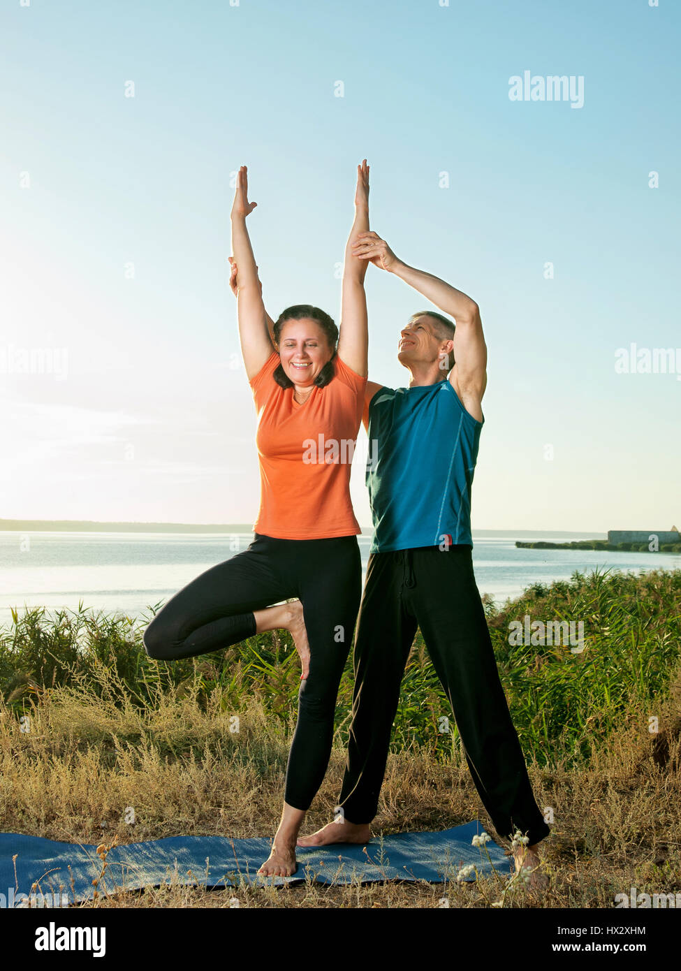 Lächelndes Paar machen Yoga Übungen im Freien Stockfoto