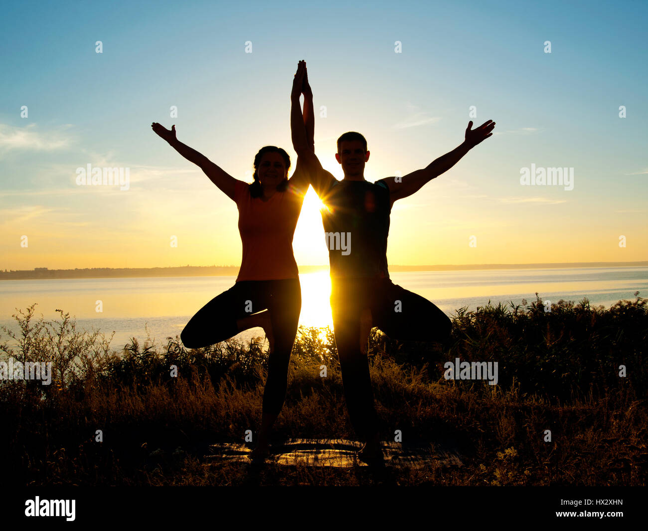 Lächelndes Paar machen Yoga Übungen im Freien Stockfoto