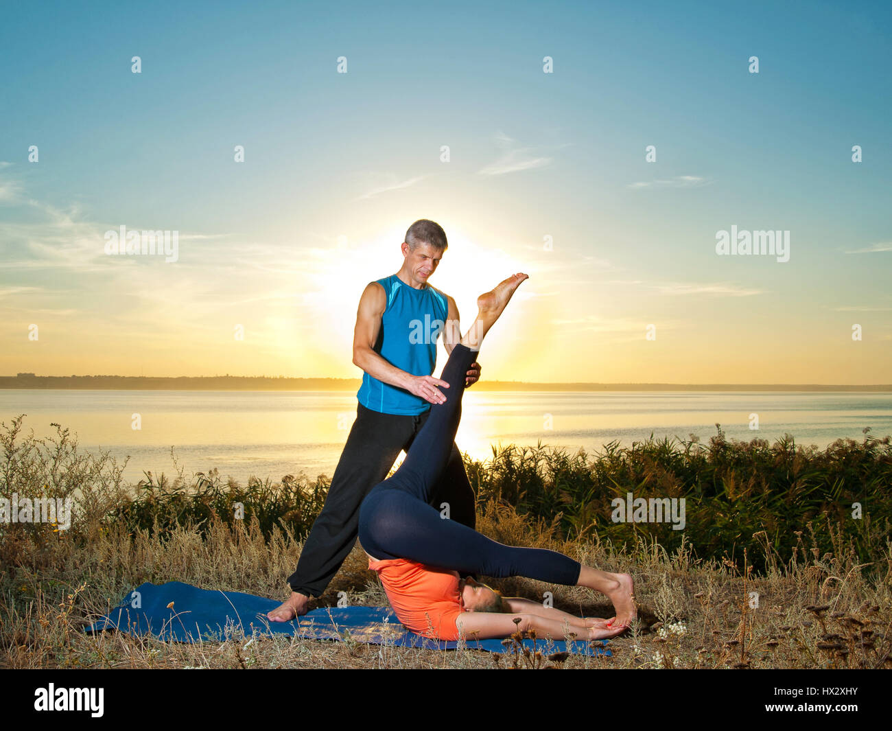 Lächelndes Paar machen Yoga Übungen im Freien Stockfoto