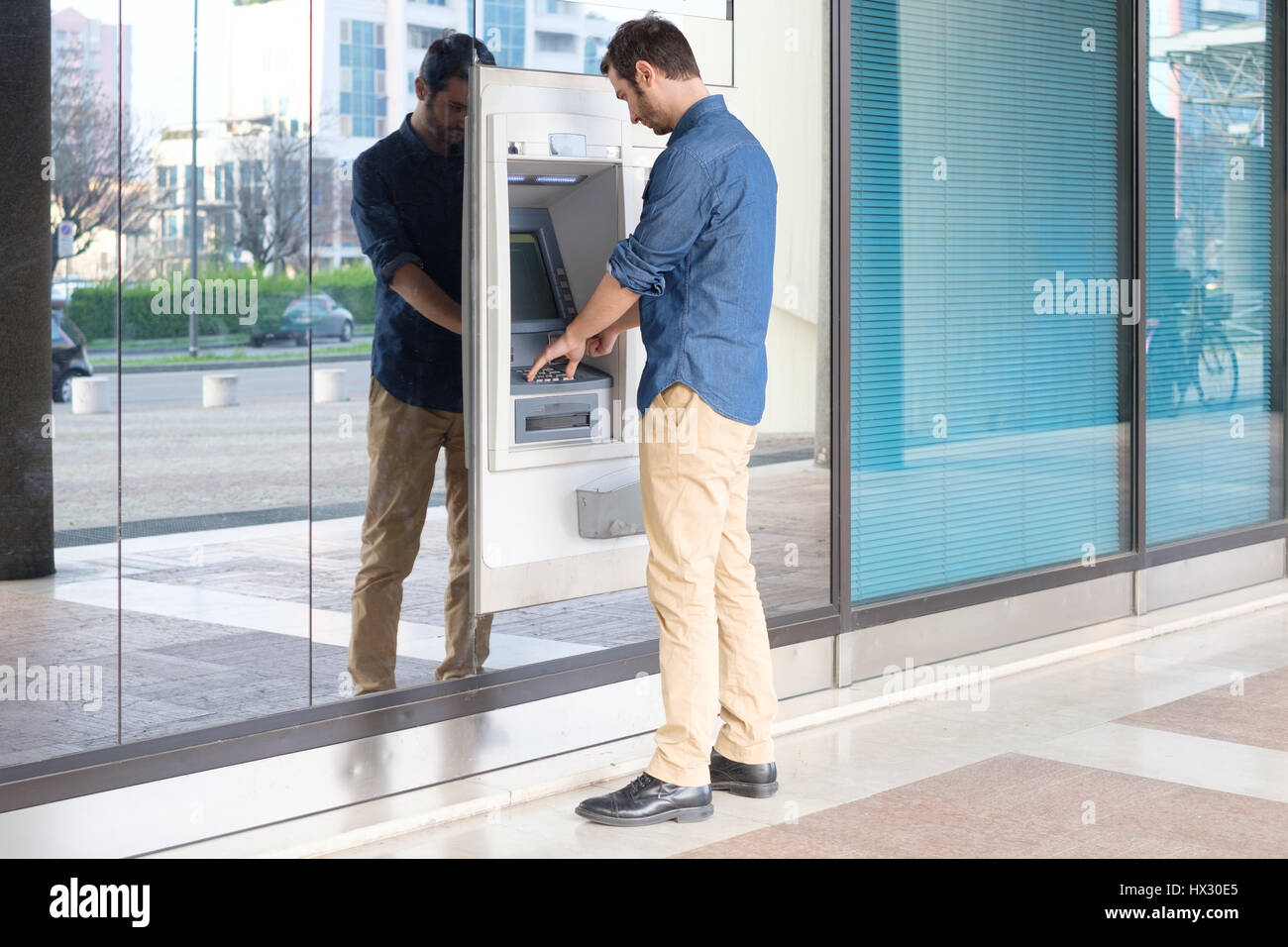 Mann mit seiner Kreditkarte in einem Geldautomaten für Bargeldbezug Stockfoto