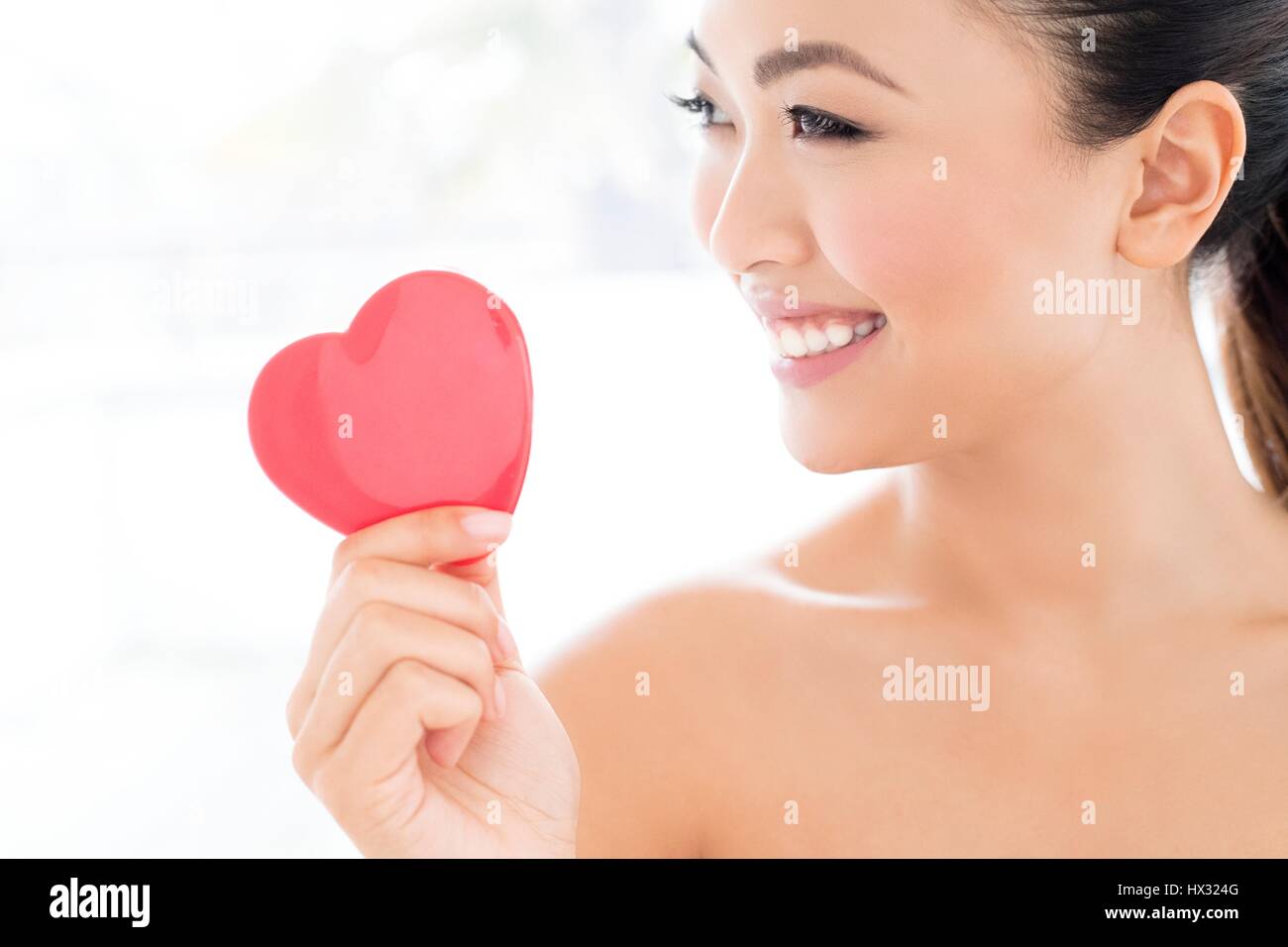 -MODELL VERÖFFENTLICHT. Junge asiatische Frau halten Herz, Portrait. Stockfoto