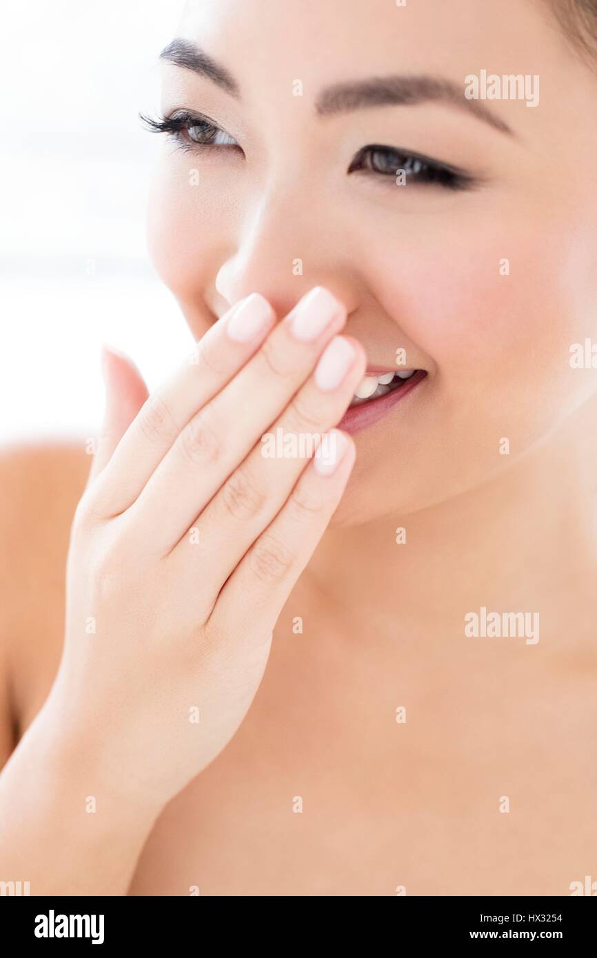 -MODELL VERÖFFENTLICHT. Junge asiatische Frau, die mit der Hand den Mund zu, Lachen Porträt. Stockfoto