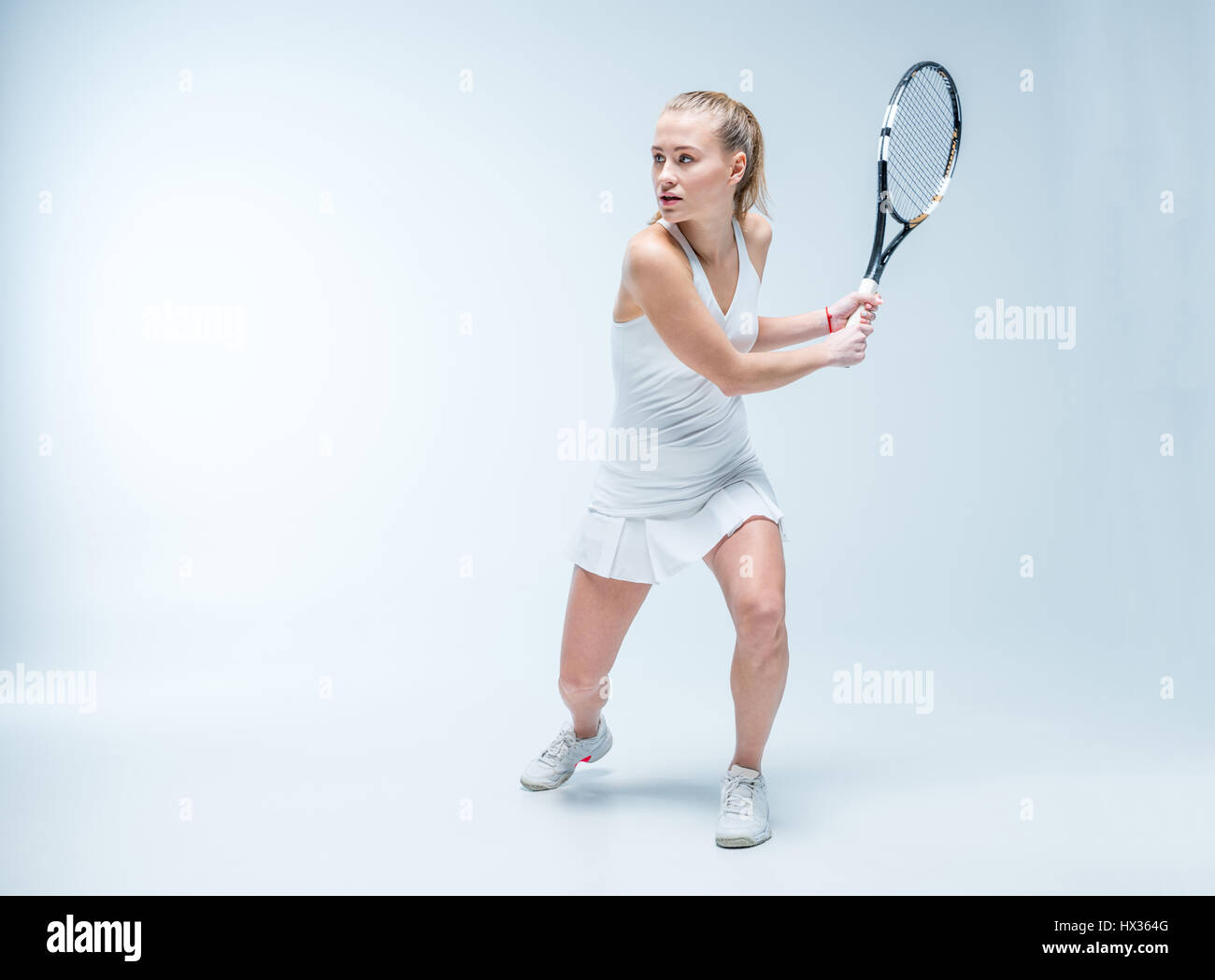 Aktive junge Frau mit dem Tennisspielen und wegsehen auf blau Stockfoto